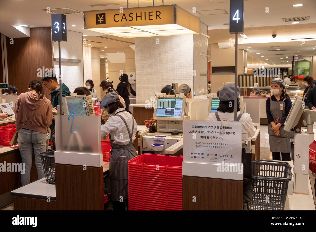 Am 2023. April bezahlen Kunden Lebensmittel an der Kasse in einer Lebensmittelhalle in Tokio in Shinjuku, Mitarbeiter tragen Masken, Japan, Asien Stockfoto