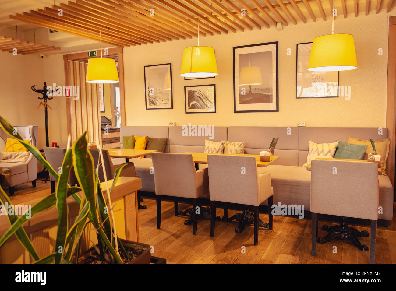 Stilvolle Café-Einrichtung. Sofa und bequeme Stühle im Restaurant. Café-Möbel im Innenbereich. Leerer Loungebereich mit warmen Lampen. Design der Hotellobby. Stockfoto