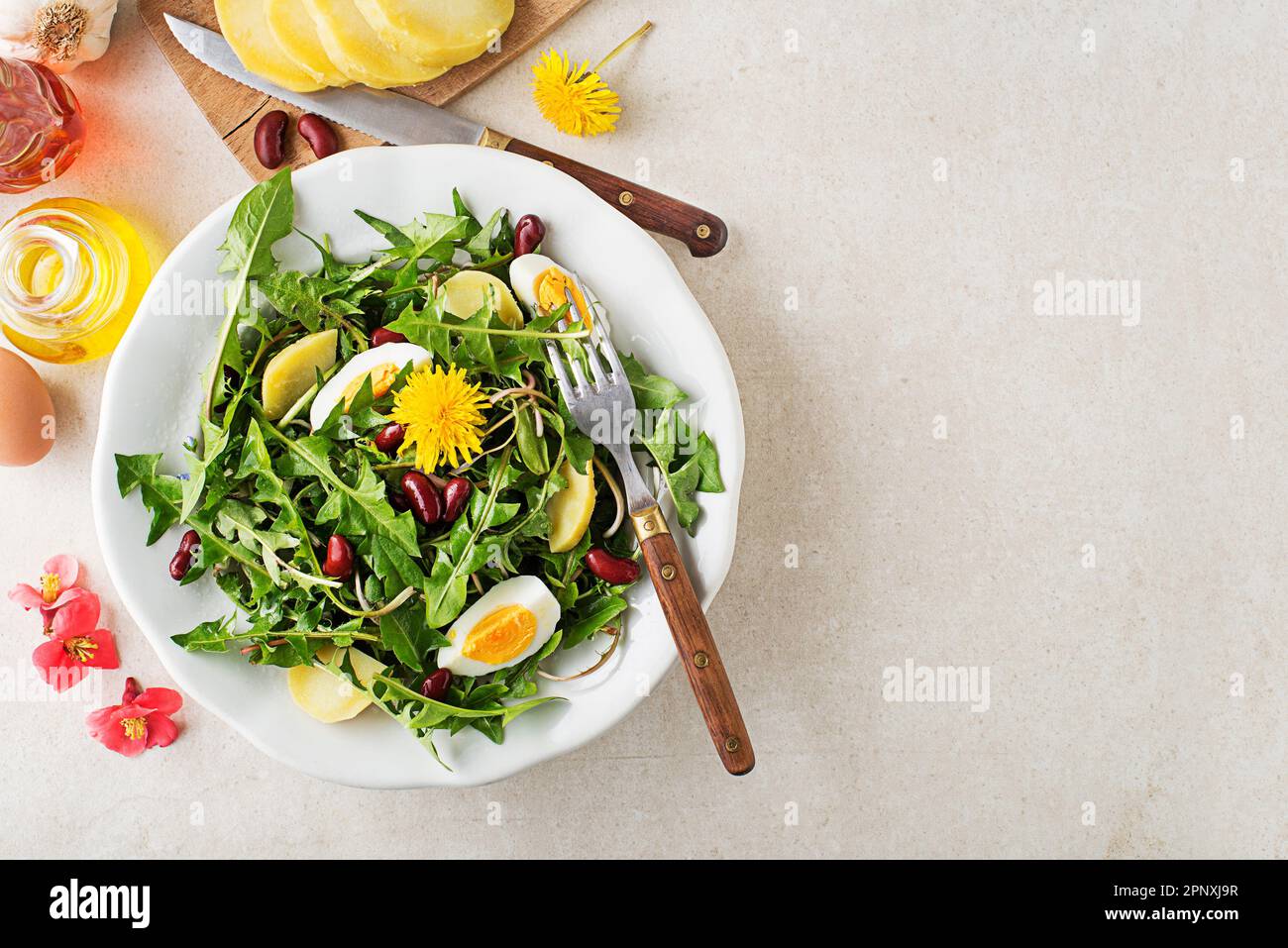 Löwenzahnsalat mit Eiern, Kartoffeln und Bohnen auf hellen Tischhintergrund Stockfoto