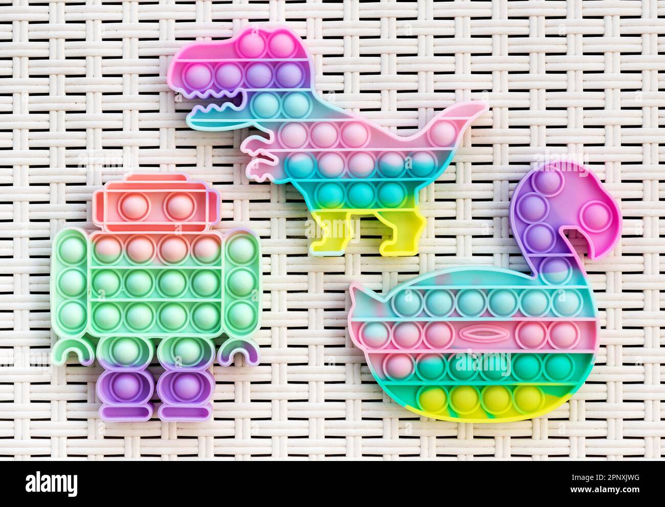 Ansicht von oben: Farbenfrohe Pop IT Anti-Stress-Spielzeuge in verschiedenen Formen, die auf einem Korbtisch aus Kunststoff platziert werden Stockfoto