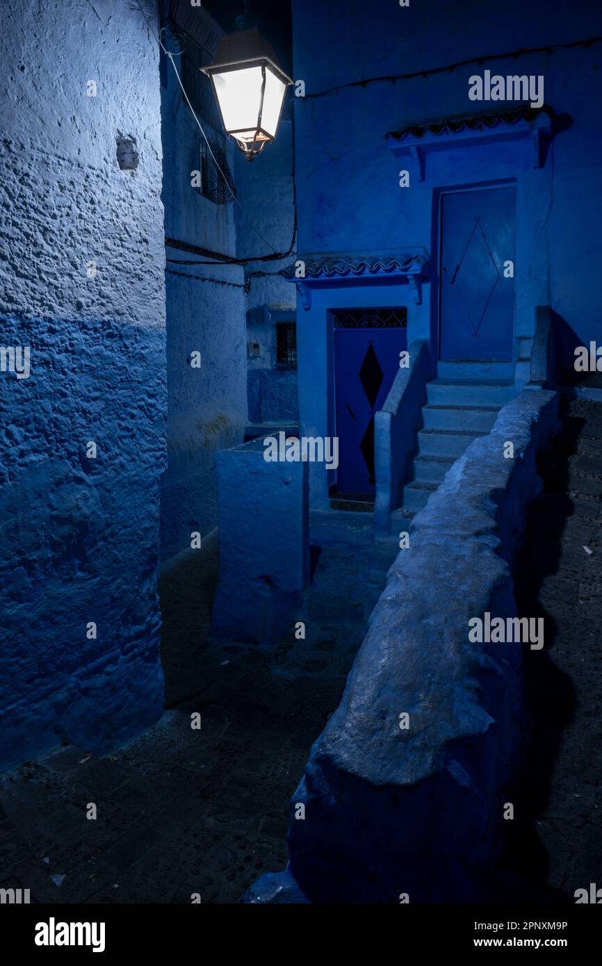 Gasse in der Stadt Chefchaouen, beleuchtet durch das künstliche Licht der Straßenlaternen. Stockfoto