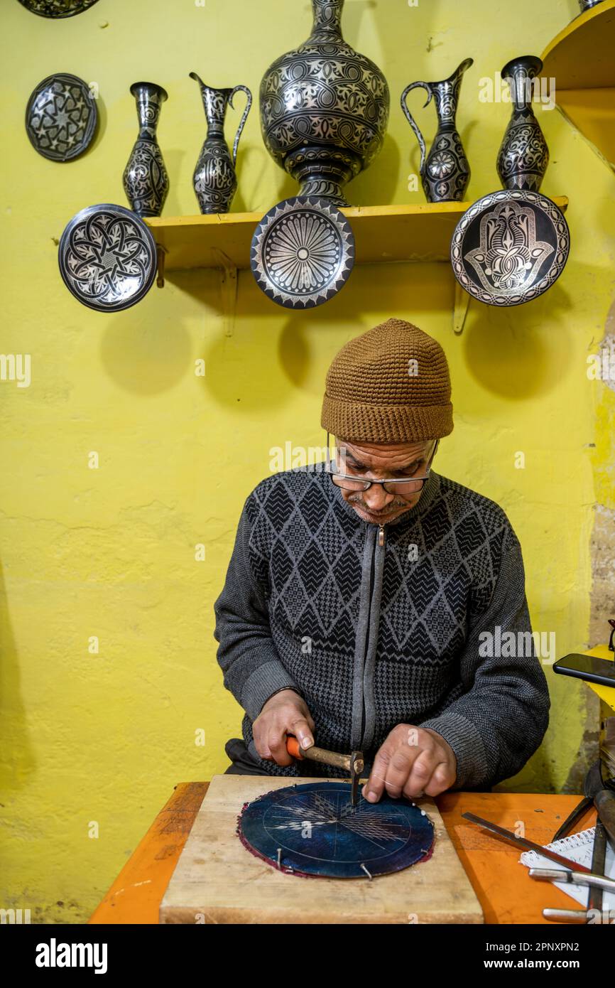 Ein Handwerker, der einen Teller mit der Damaszene-Technik dekoriert. Stockfoto