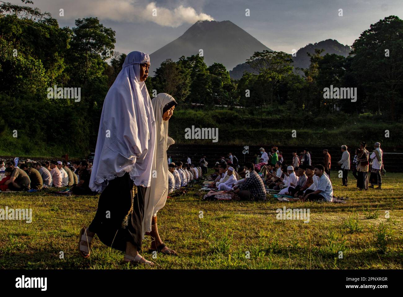 Sleman, Yogyakarta, Indonesien. 21. April 2023. Zwei indonesische muslimische Frauen gehen zu Fuß, um Eid al-Fitr 1944 Hijriyah Gebete mit Mount Merapi im Hintergrund in Kaliurang, Sleman, Yogyakarta, Indonesien, Freitag, 21. April 2023 in Yogyakarta, Indonesien. Moslems auf der ganzen Welt feiern Eid mit ihren Familien mit Partys zum Ende des Ramadan, des heiligen Monats des Fastens. (Kreditbild: © Slamet Riyadi/ZUMA Press Wire) NUR REDAKTIONELLE VERWENDUNG! Nicht für den kommerziellen GEBRAUCH! Stockfoto