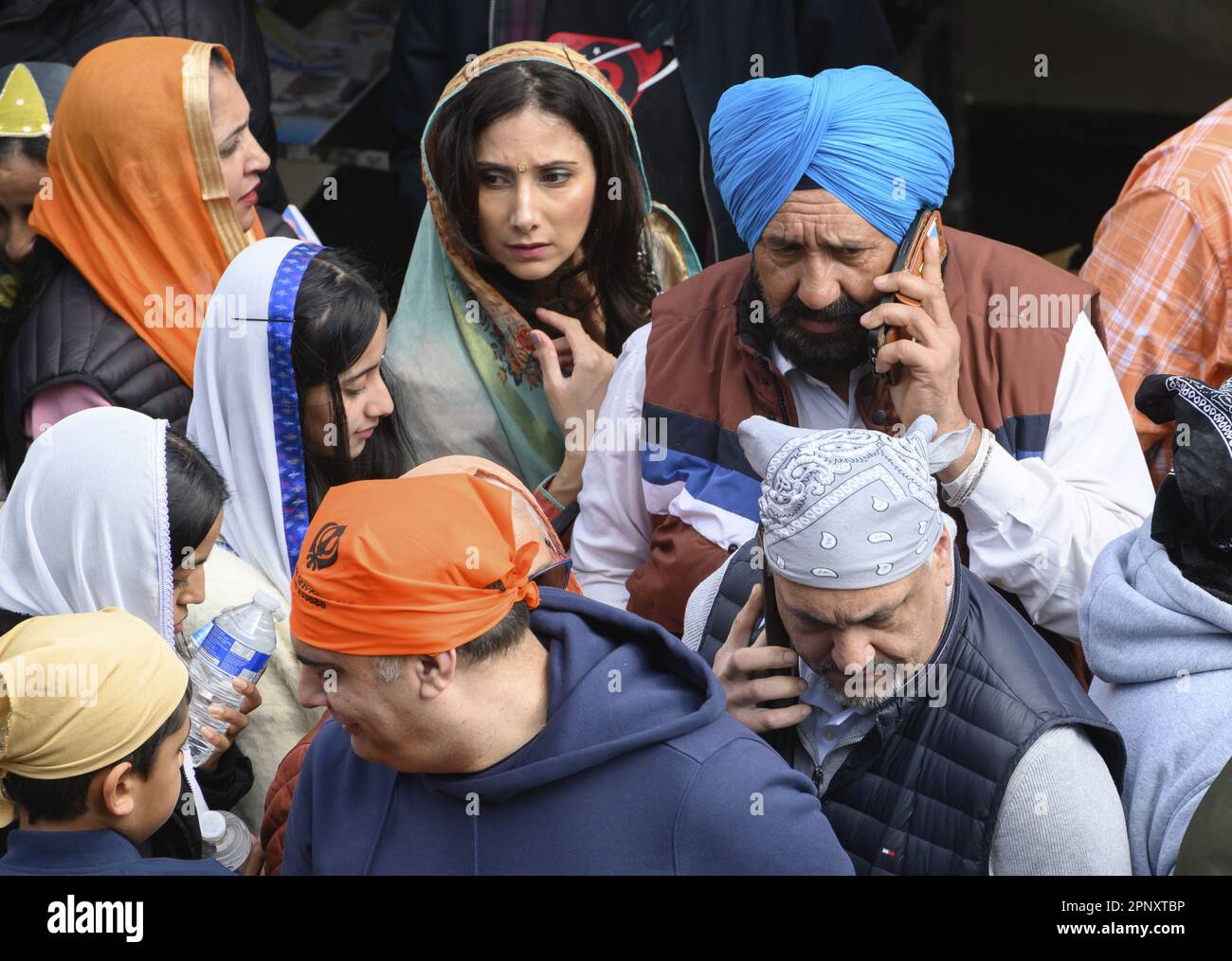 Gravesend, Kent, Großbritannien. Sikh-Männer bedienen ihre Mobiltelefone bei den jährlichen Vaisakhi-Feierlichkeiten im Stadtzentrum. 15. April 2023 Stockfoto
