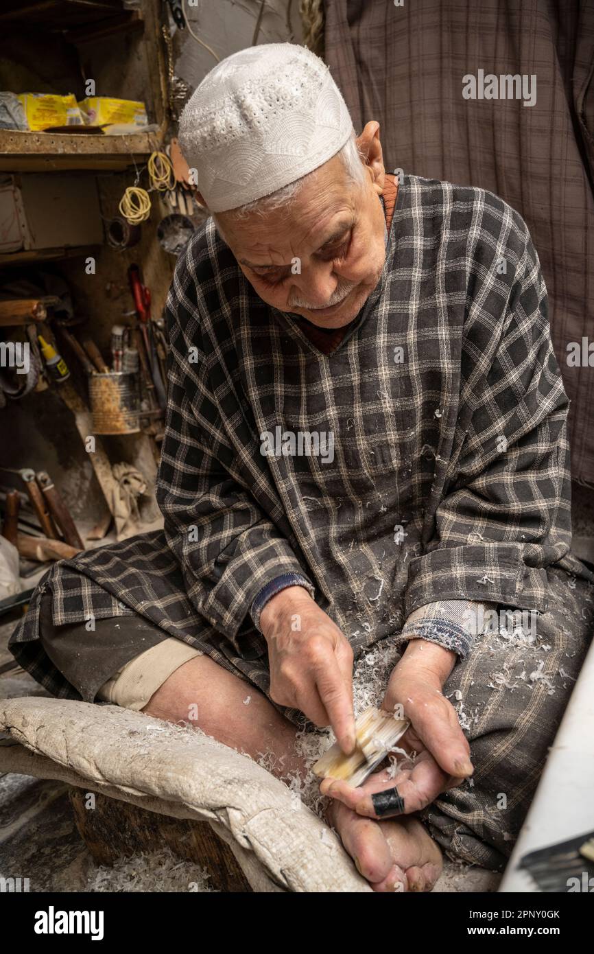 Ein Handwerker, der ein Kuhhorn von Hand schneidet, um handgemachte Kämme zu machen. Stockfoto