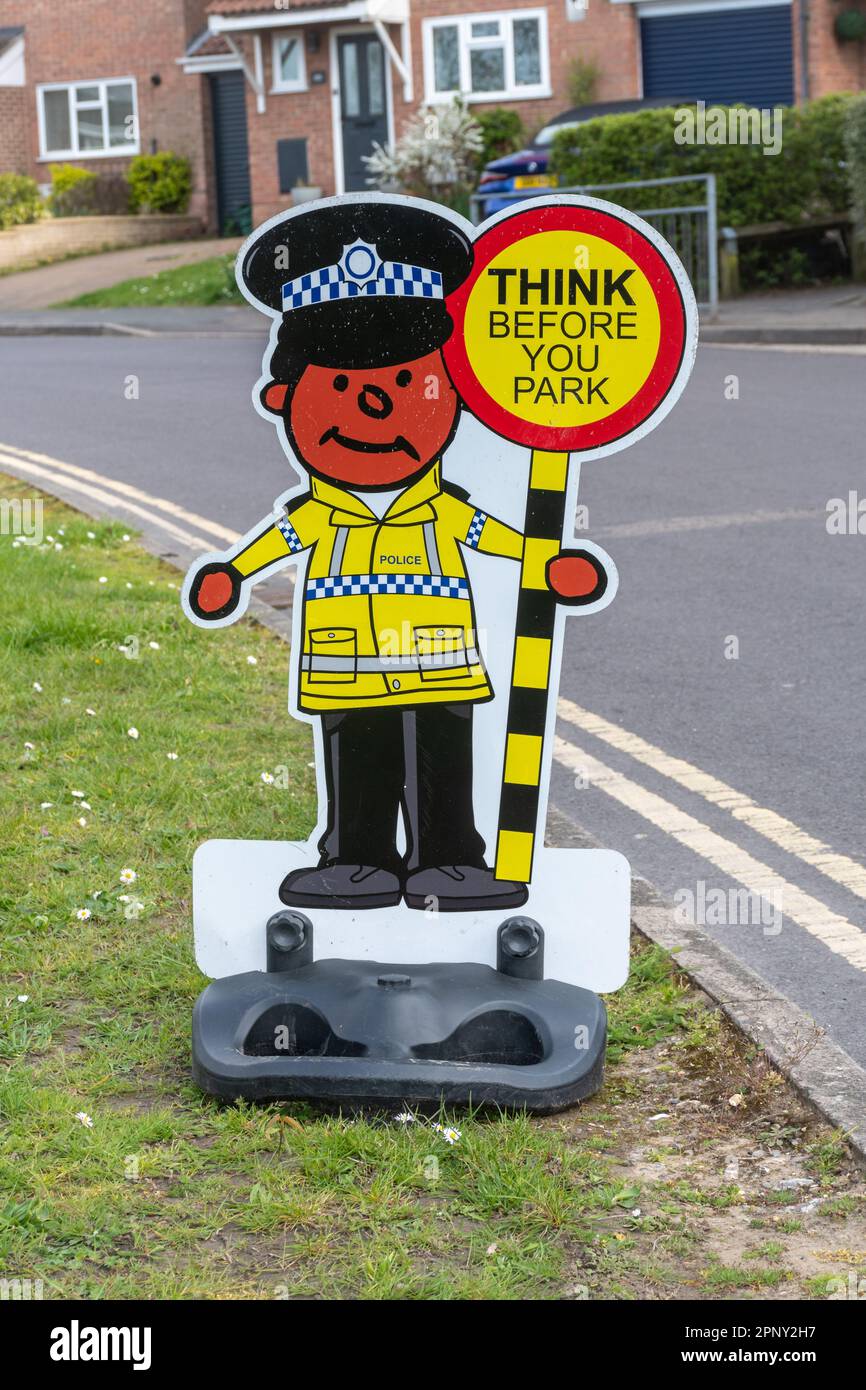 Ein lustiges Schild vor einer Schule mit einem Polizisten und einem Lutscher, die das Schild lesen. Denken Sie daran, bevor Sie parken, England, Großbritannien. Verkehrssicherheit an der Schule Stockfoto