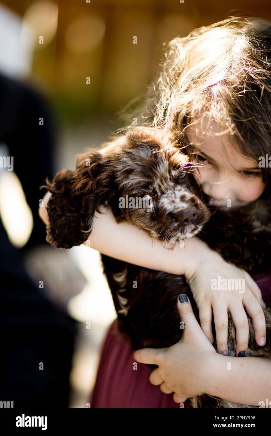 Achtjähriges Mädchen mit Hündchen und Umarmung in San Diego Stockfoto