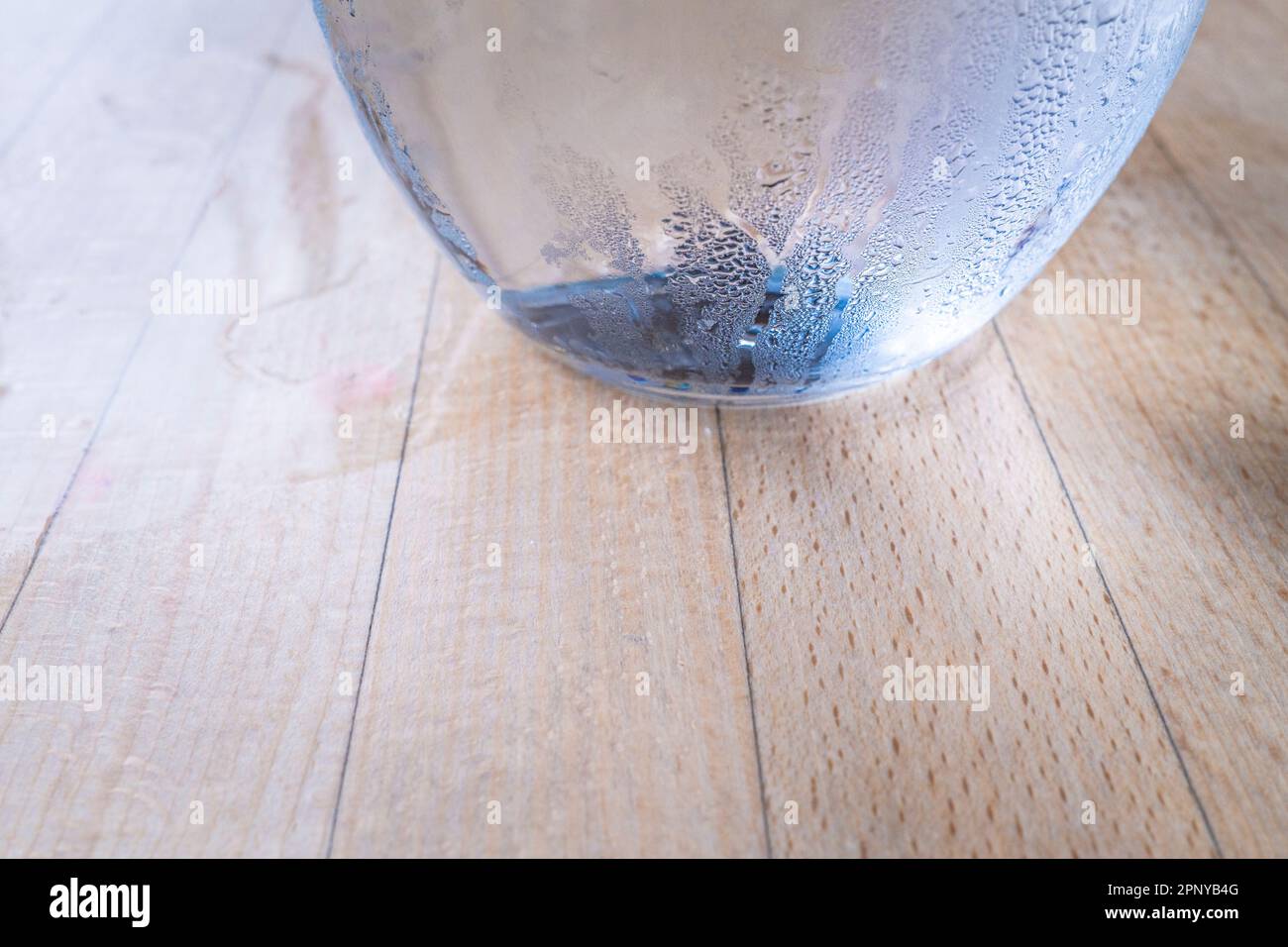 Eine Nahaufnahme des Kondensats an der Seite einer Glaskanne mit Wasser auf einem Tisch. Stockfoto