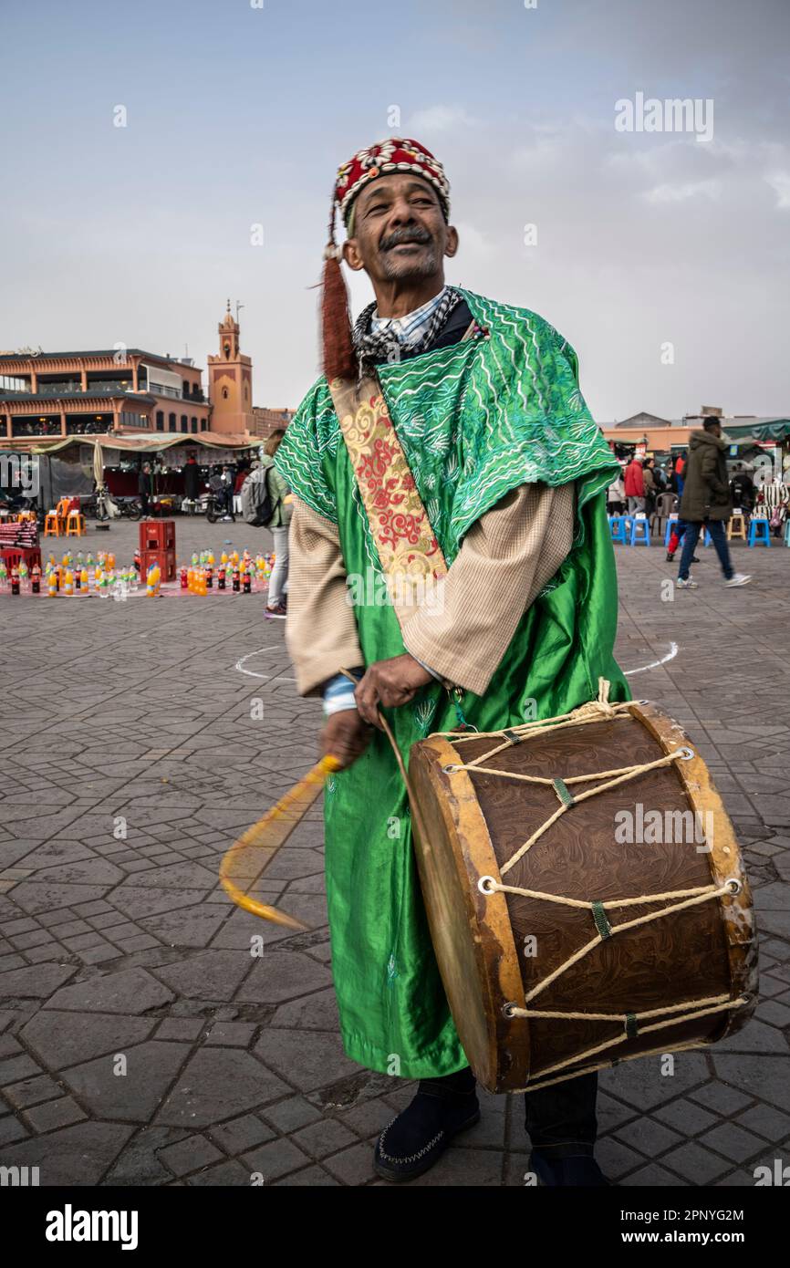 Ein Mann in traditioneller marokkanischer Kleidung spielt auf dem Platz Jemaa el-Fnaa in Marrakesch die Trommel. Stockfoto