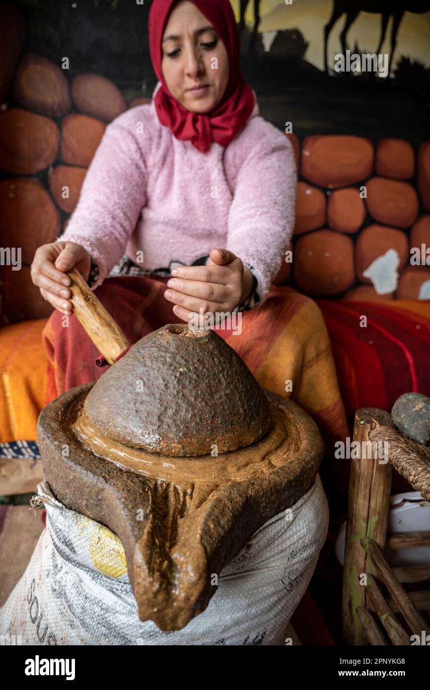 Berber-Lady, die Arganpaste mit einer manuellen Steinschleifmaschine herstellt. Stockfoto