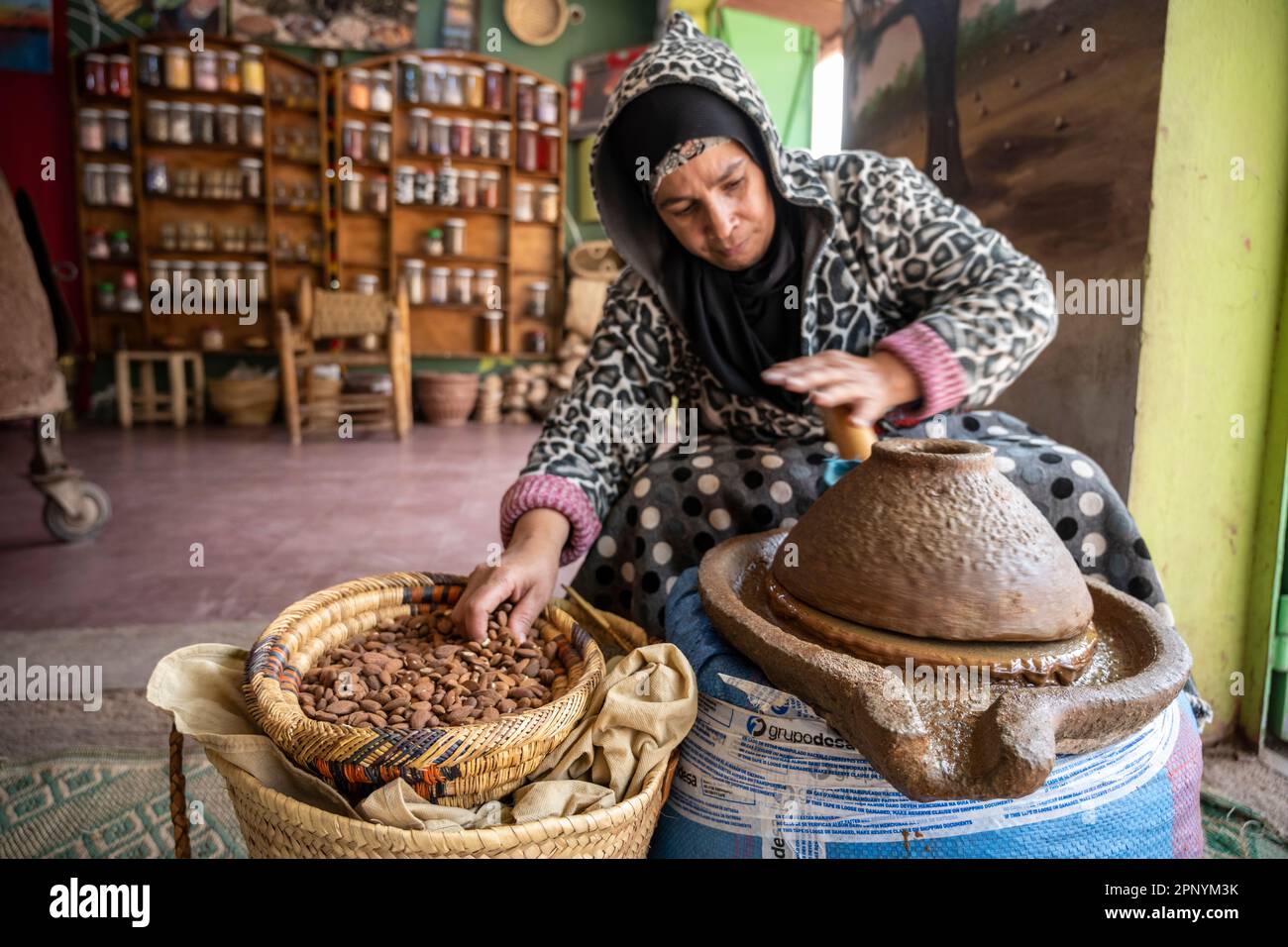 Berber-Lady, die Arganpaste mit einer manuellen Steinschleifmaschine herstellt. Stockfoto