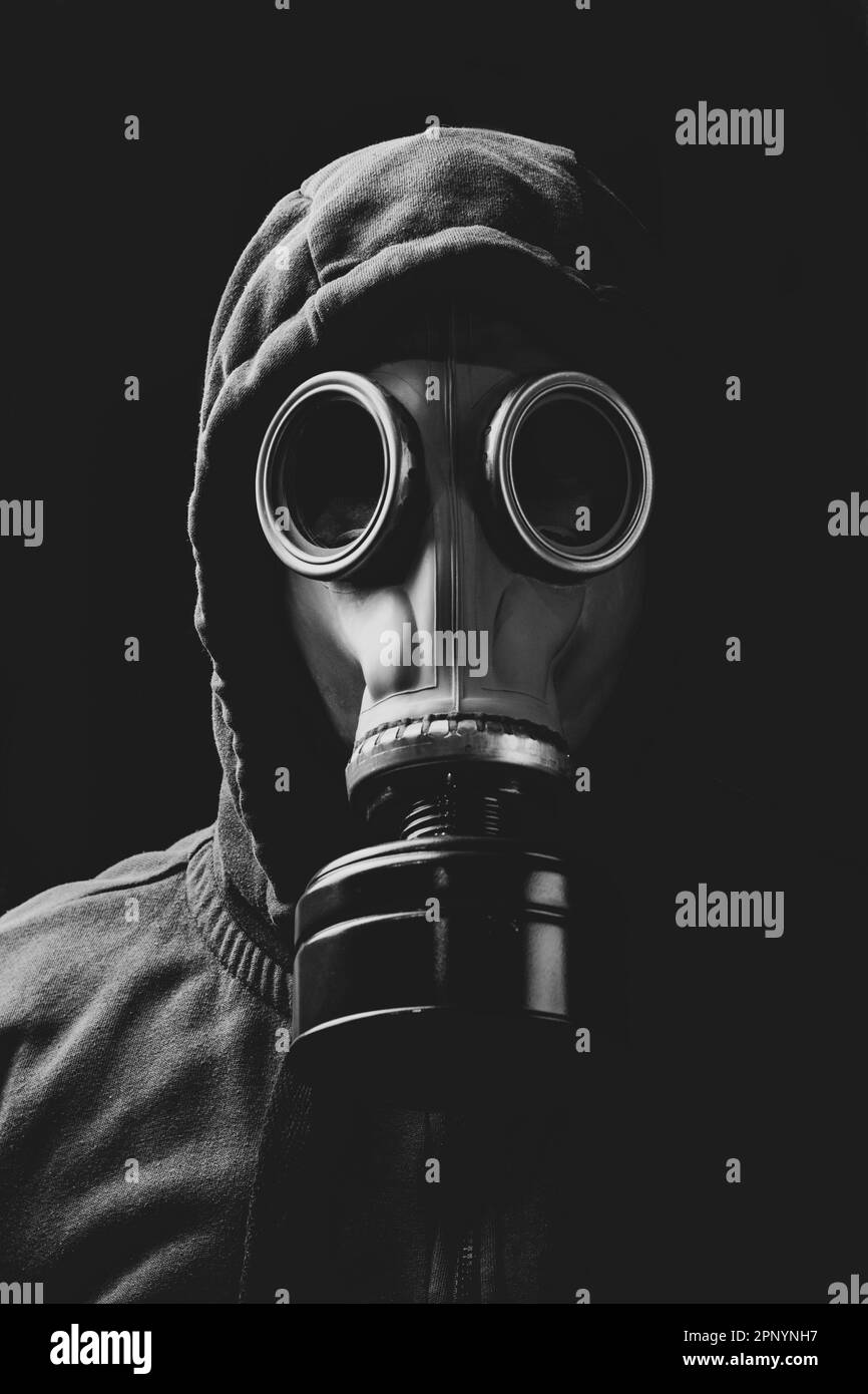 Ein Mann in einer Kapuze und in einer Gasmaske in Rauchwolken. Stockfoto
