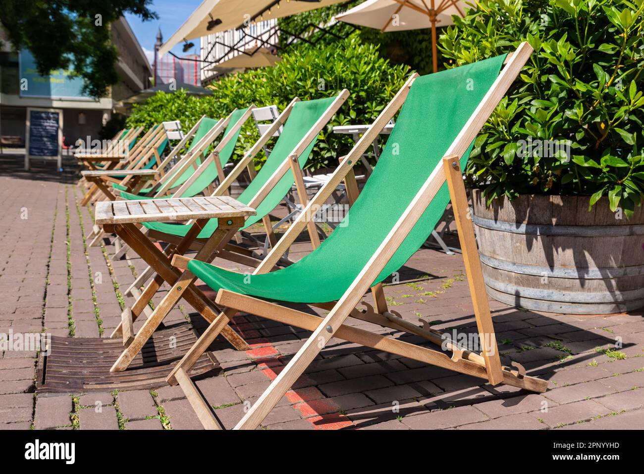 Grüne, leere Oldtimer-Liegestühle Café Entspannen Sie sich am Sonnentag am Ballhoffplatz in der Altstadt von Hannover an warmen Sonnentagen in Reihe Stockfoto