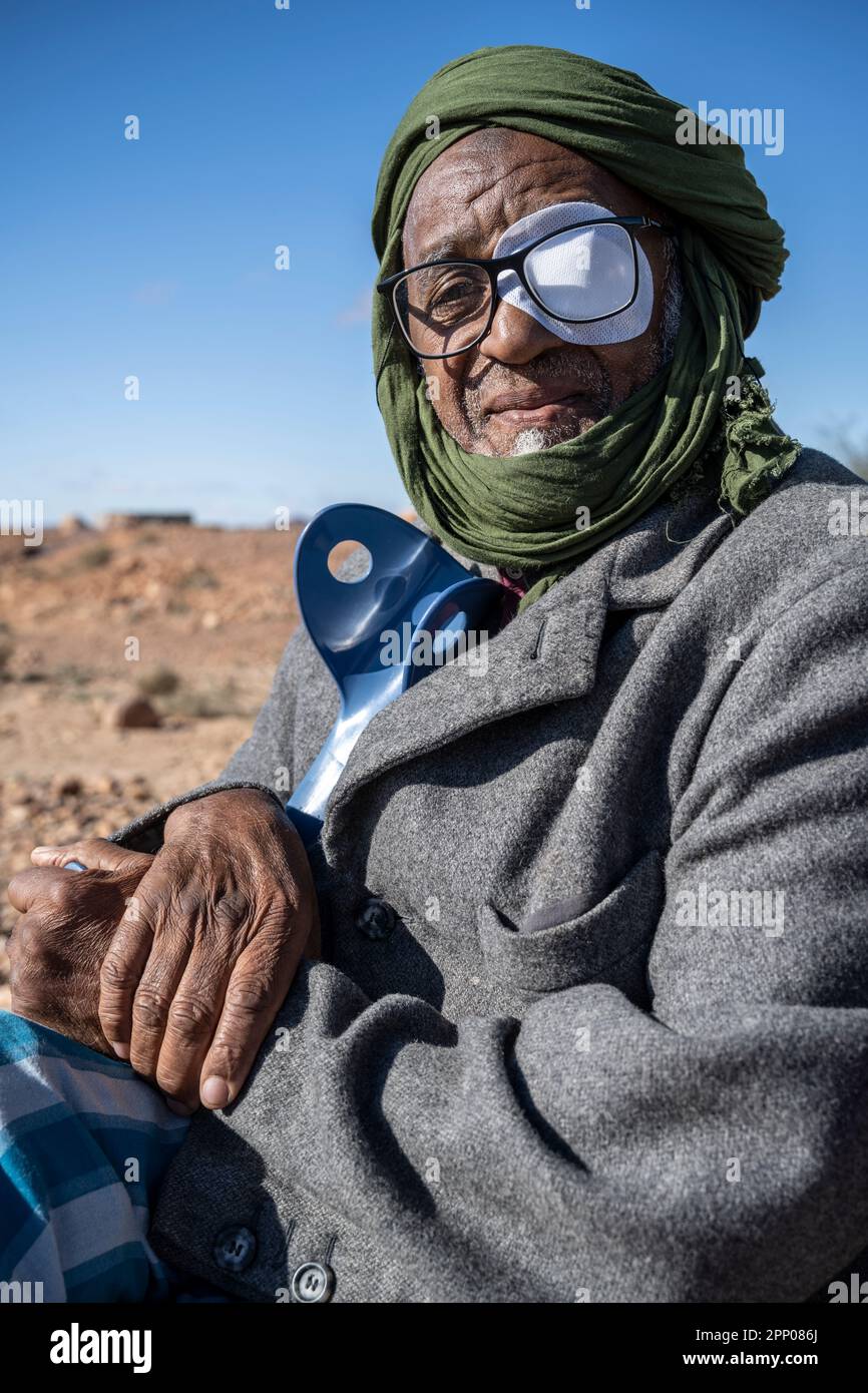 Porträt eines älteren Berbers, mit einem Auge bedeckt und auf Krücken, gekleidet in traditioneller Djellaba und Turban. Stockfoto