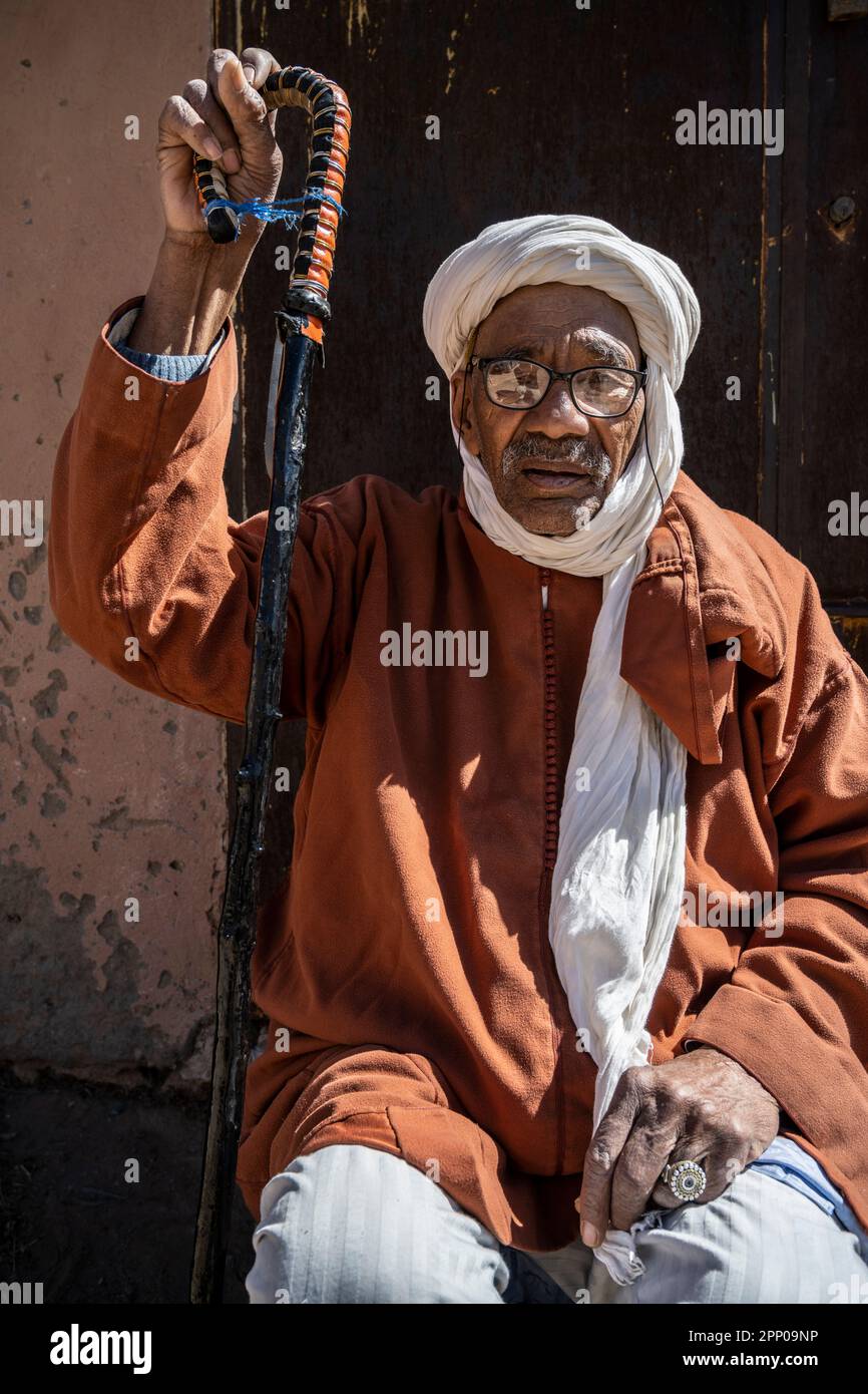 Porträt eines alten Mannes in traditioneller Kleidung, der sich an einen Stock lehnt. Stockfoto