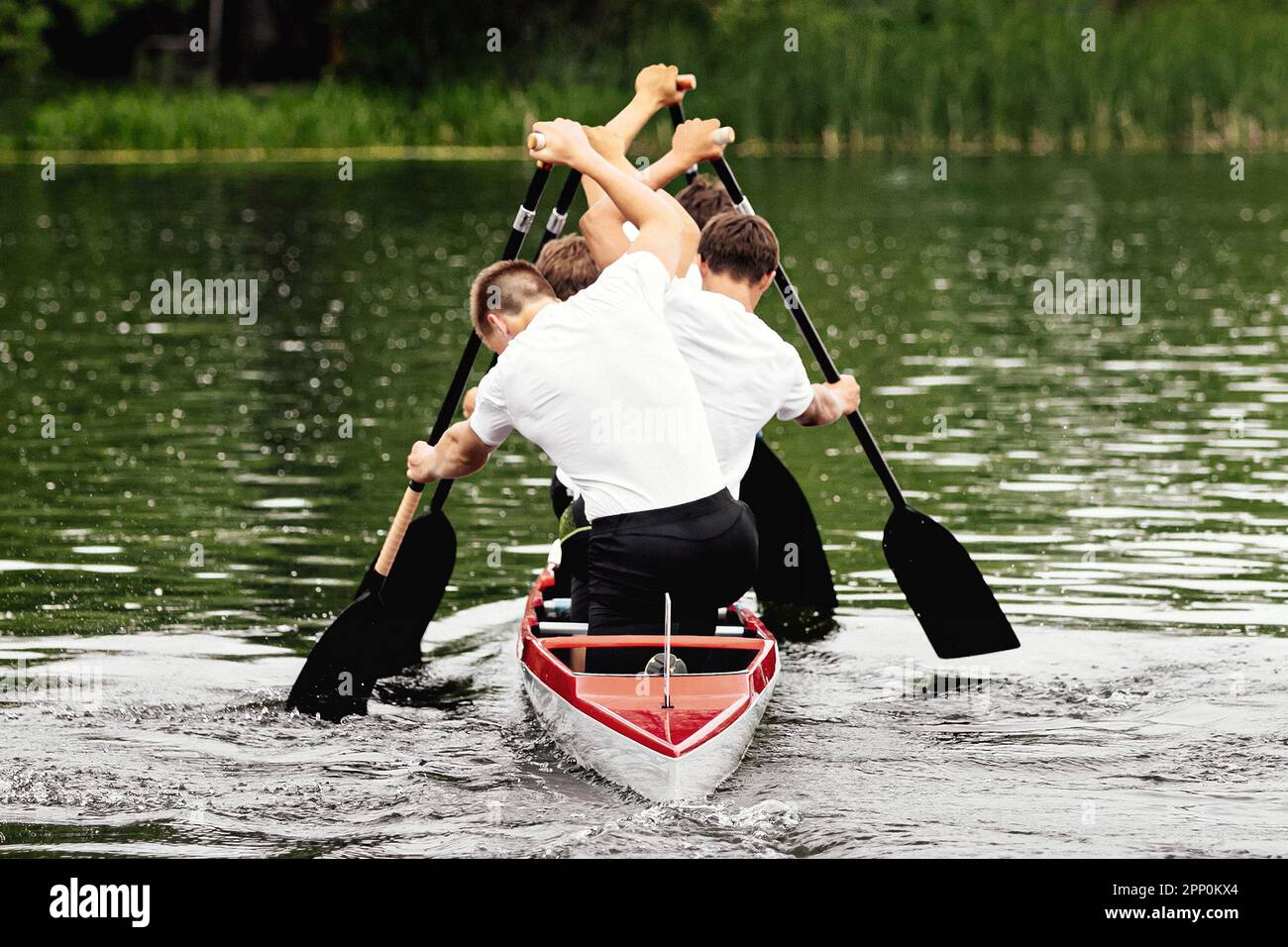 Rückansicht männlicher Kanufahrer auf Kanu vier beim Kanufahrrennen, Sportspiele im Sommer Stockfoto