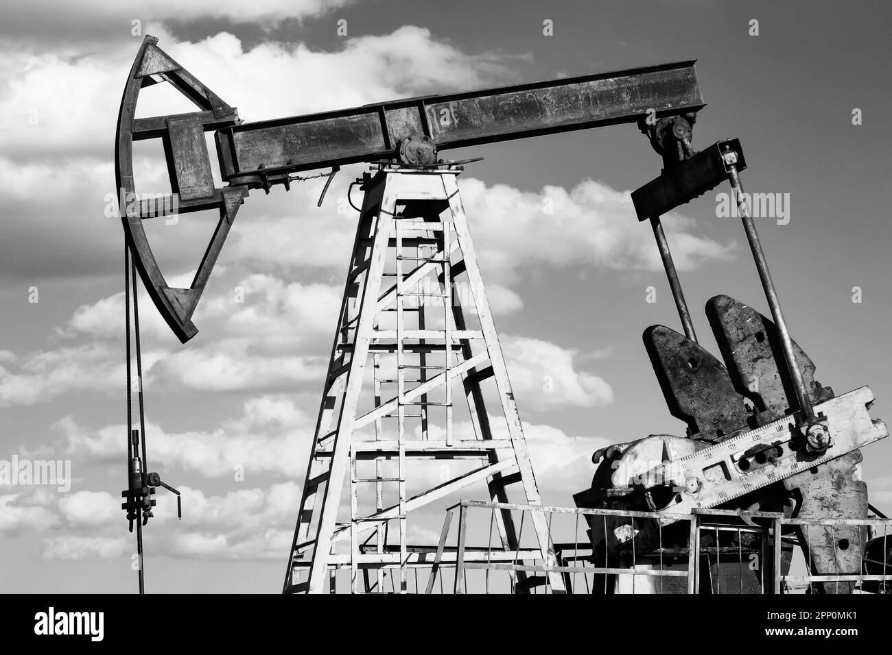 Ölförderanlage auf einem Hügel vor einem blauen Himmel mit wunderschönen weißen Wolken. Friedliche Landschaft Stockfoto