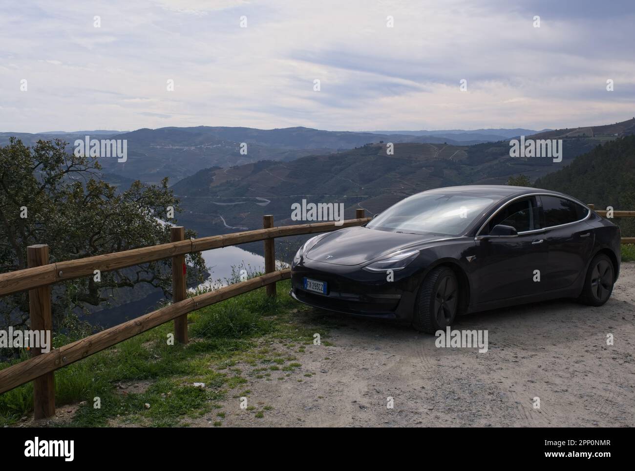 Sao Mamede de Ribatua, Portugal - 16. März 2023: Wunderschöne Landschaft vom Miradouro do Ujo. Statische Aufnahme eines soliden schwarzen Tesla Model 3. Getönter Wind Stockfoto
