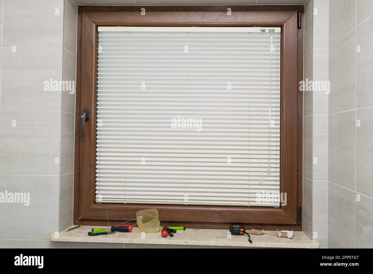 Ansicht eines braunen Kunststofffensters mit montierter Blende Stockfoto