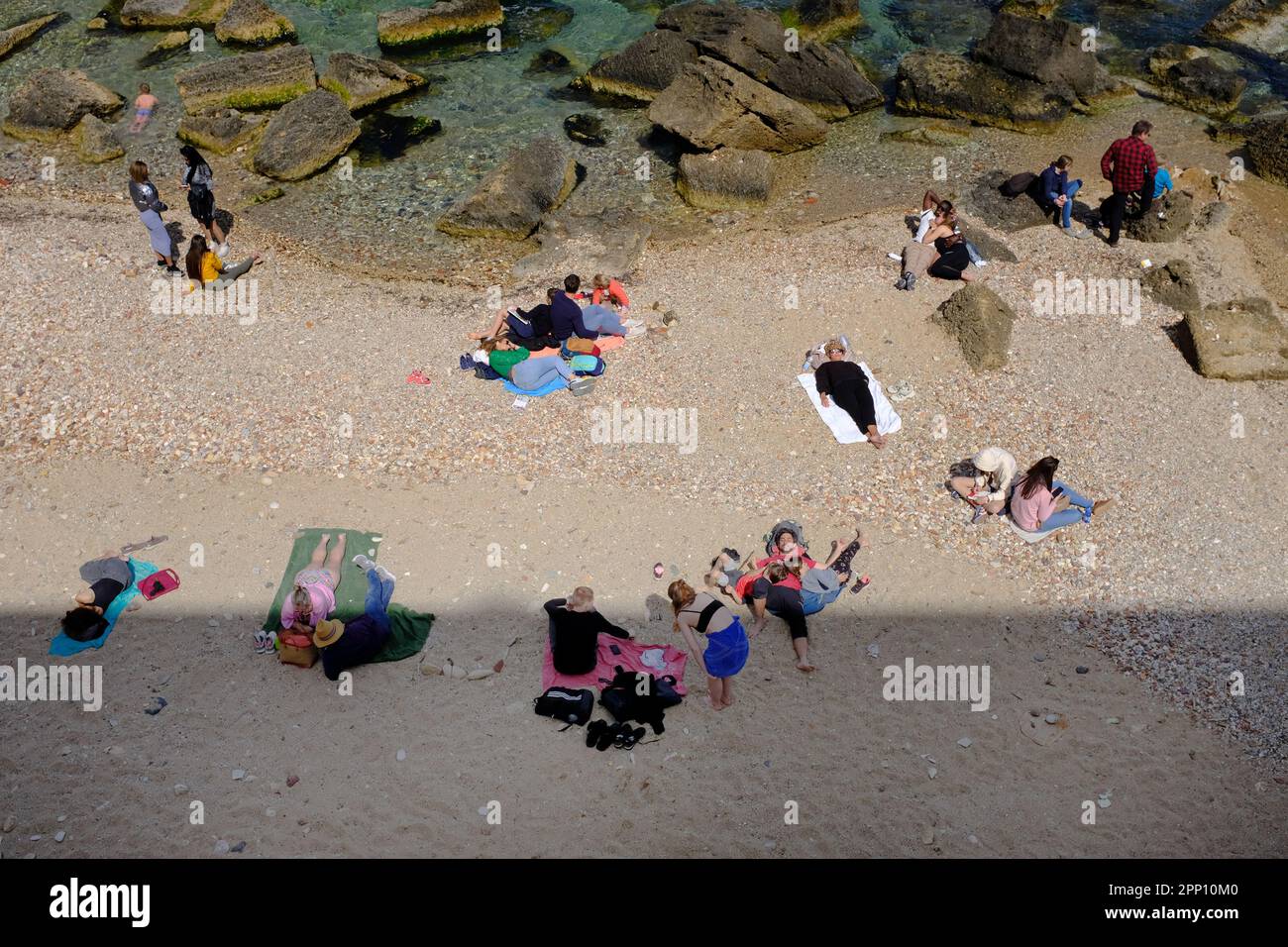 Touristen sonnen sich am Kleinstadtstrand in Syrakus, Sizilien. Einige in der Sonne, andere im Schatten. Stockfoto
