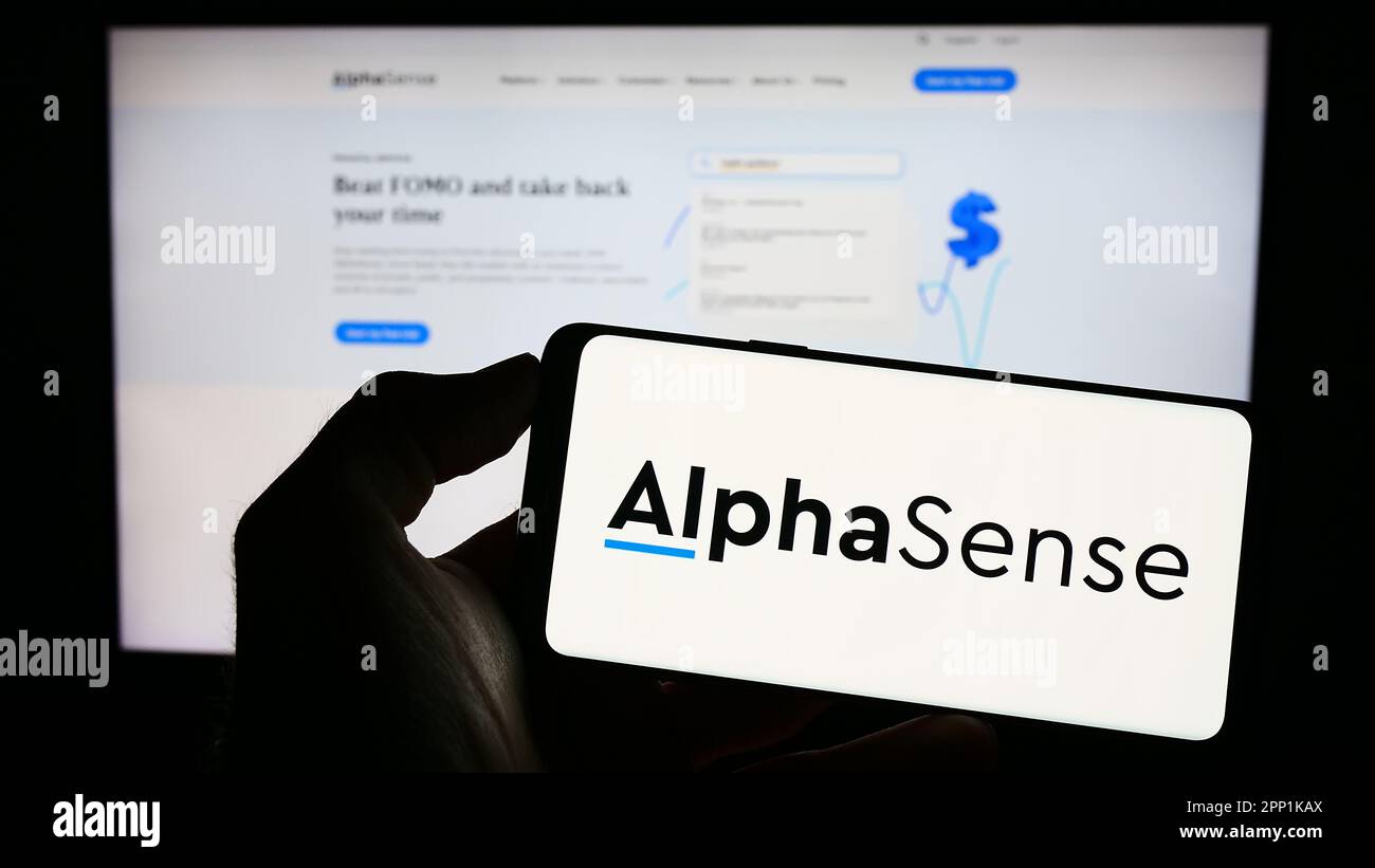 Person, die ein Mobiltelefon mit dem Logo des US-amerikanischen Marktinformationsunternehmens Alphasense Inc. Auf dem Bildschirm vor der Webseite hält. Konzentrieren Sie sich auf das Display des Telefons. Stockfoto