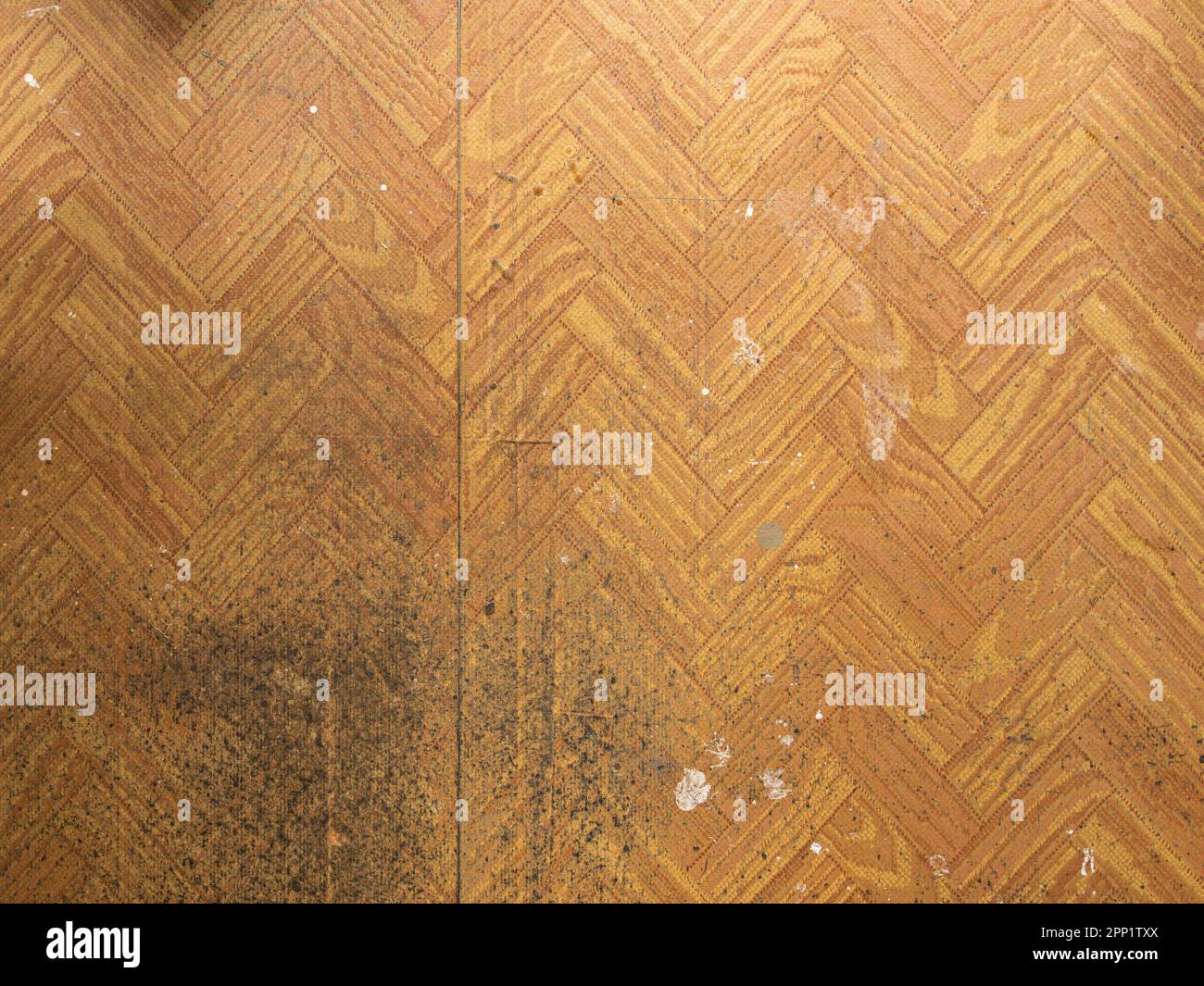 Fußboden aus Polyvinylchlorid (PVC) mit vielen Schmutzstellen aus der Renovierung. Weiße Wandfarbe auf dem Boden. Billiges Material mit Holzoptik. Stockfoto