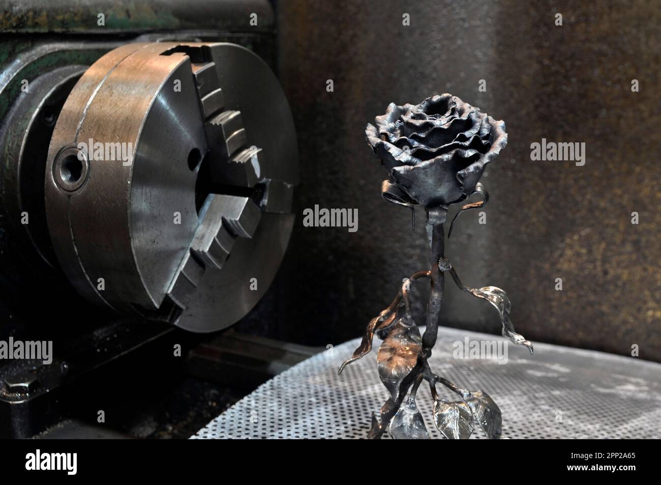 Rose von Hand geschmiedet. Diese handgefertigte Rose ist aus Metall geschmiedet, vor dem Hintergrund eines Drehbohrfutters. Stockfoto