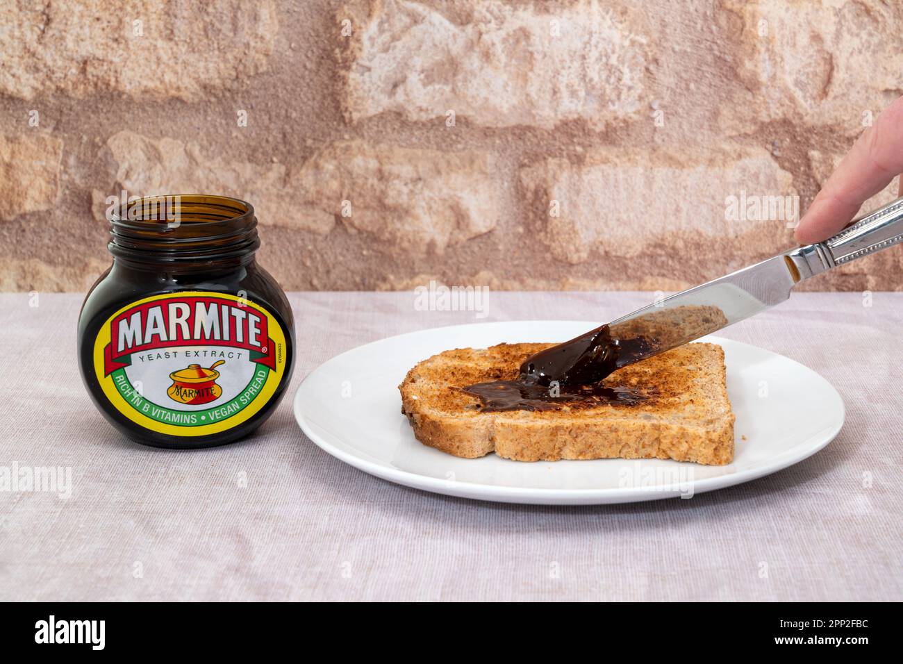 London, Vereinigtes Königreich - 21. März 2023 : Marmite wird auf einer Scheibe getoastetes Brot gestreut. Marmite ist ein Hefeextrakt, der reich an Vitamin B ist Stockfoto