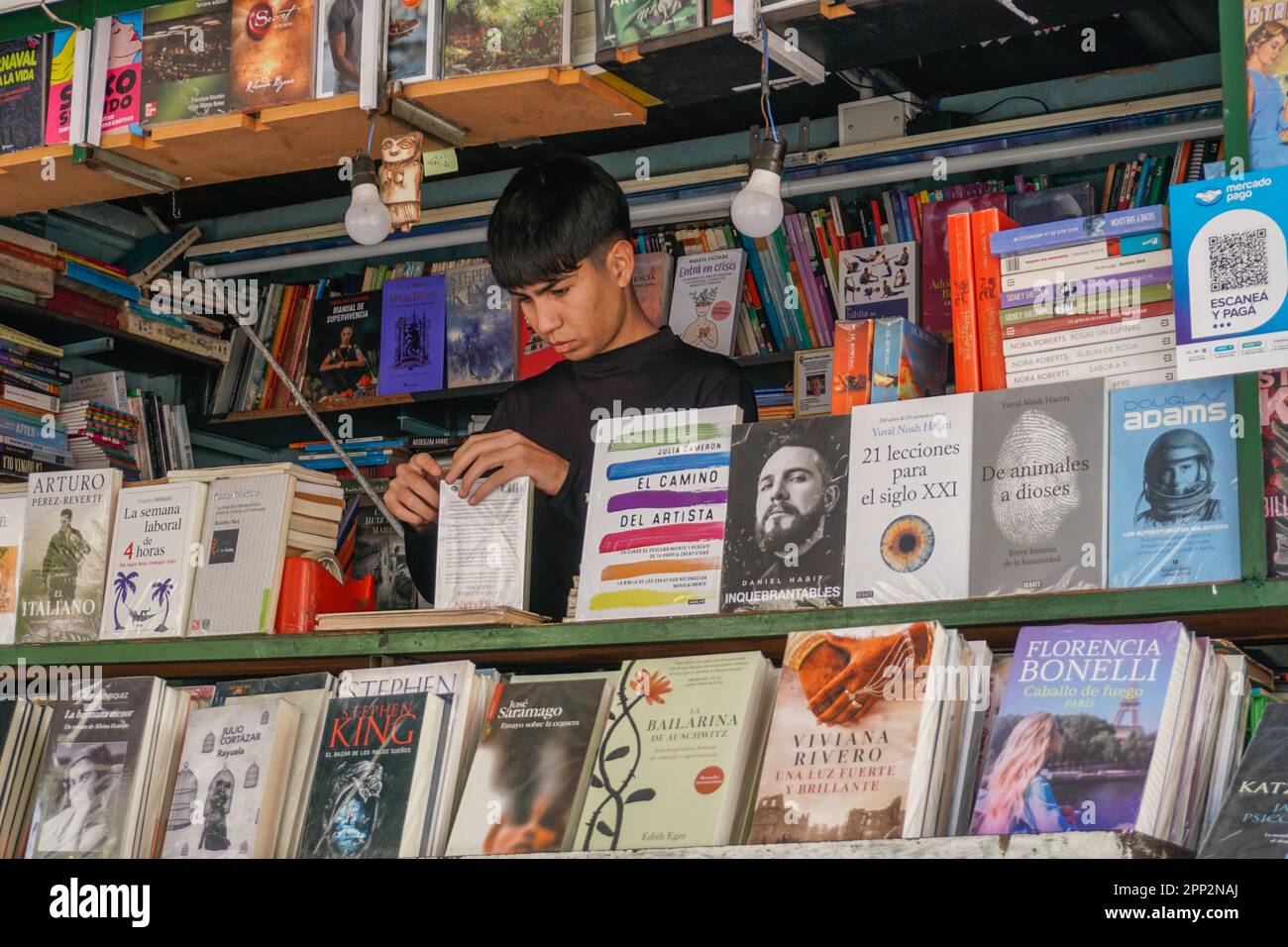 Román Molina, 17, verpackt Bücher in Plastiktüten an einem Buchmarkt in Buenos Aires, Argentinien, am 13. Oktober 2022. Jeden Tag stellt Molina die Bestellungen zusammen, die er über soziale Medien erhält. Er sagt, dass sein Lieblingsteil der Arbeit die Interaktion mit Kunden sei, die manchmal eine „gute Stimmung“ haben und Bücher empfehlen. (Lucila Pellettieri/Global Press Journal) Stockfoto