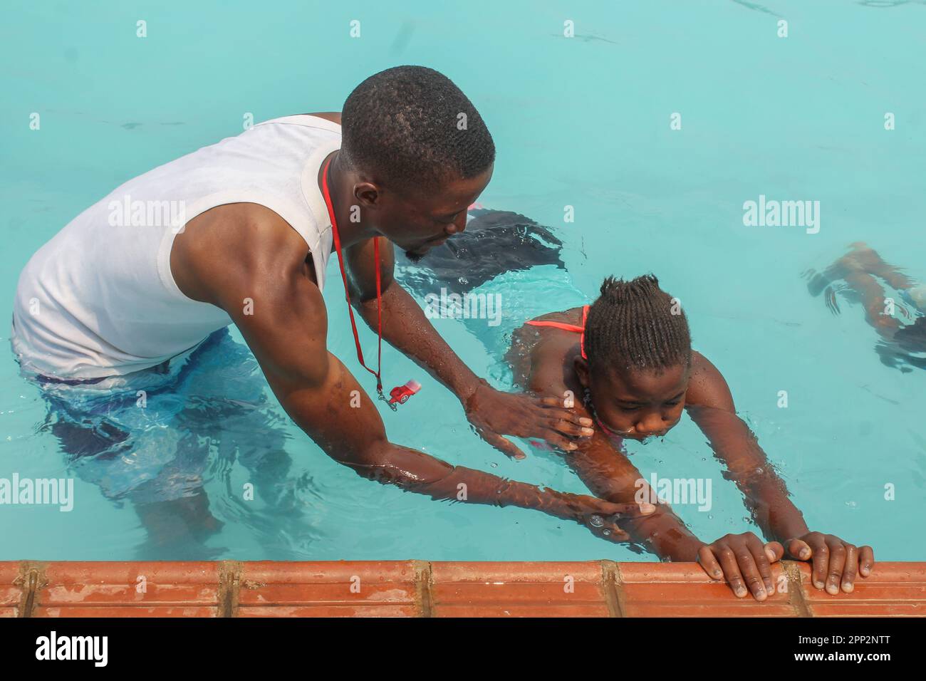 Chimuka Mukonka, links, bringt Blessings Banda, 12, am 8. Oktober 2022 das Schwimmen an der Meerjungfrauen-Schwimmakademie in Lusaka, Sambia, bei. Mukonka, der die Akademie gründete, sagt: „Wir hören von Menschen, die ertrinken, und wir können Leben retten, indem wir der nächsten Generation das Schwimmen beibringen.“ (Prudence Phiri/Global Press Journal) Stockfoto