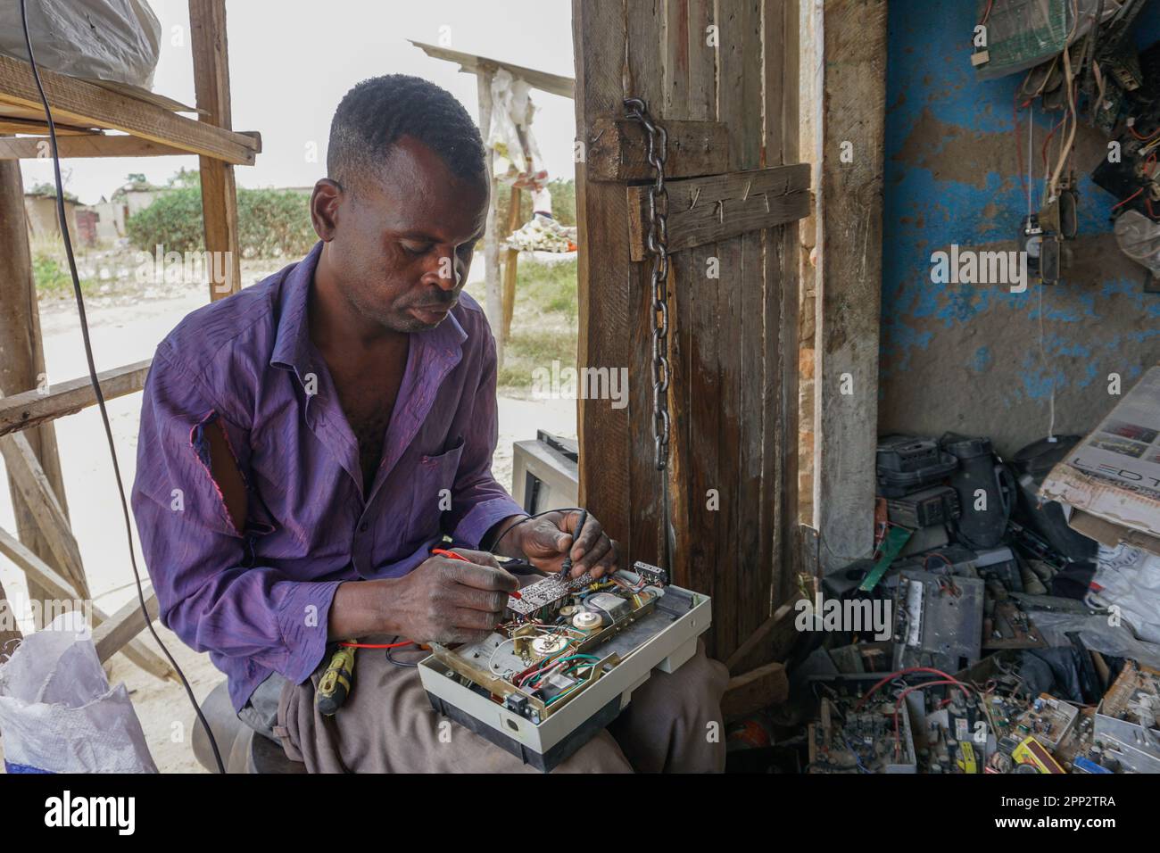 Elijah Chirongwe repariert am 21. Oktober 2022 ein Funkgerät in seiner provisorischen Werkstatt in Harare, Simbabwe. Chirongwe sagt, er habe vor 10 Jahren damit begonnen, elektrische Geräte zu reparieren, nachdem ein Einzelhandelsgeschäft ihn entlassen hatte. (Gamuchirai Masiyiwa/Global Press Journal) Stockfoto