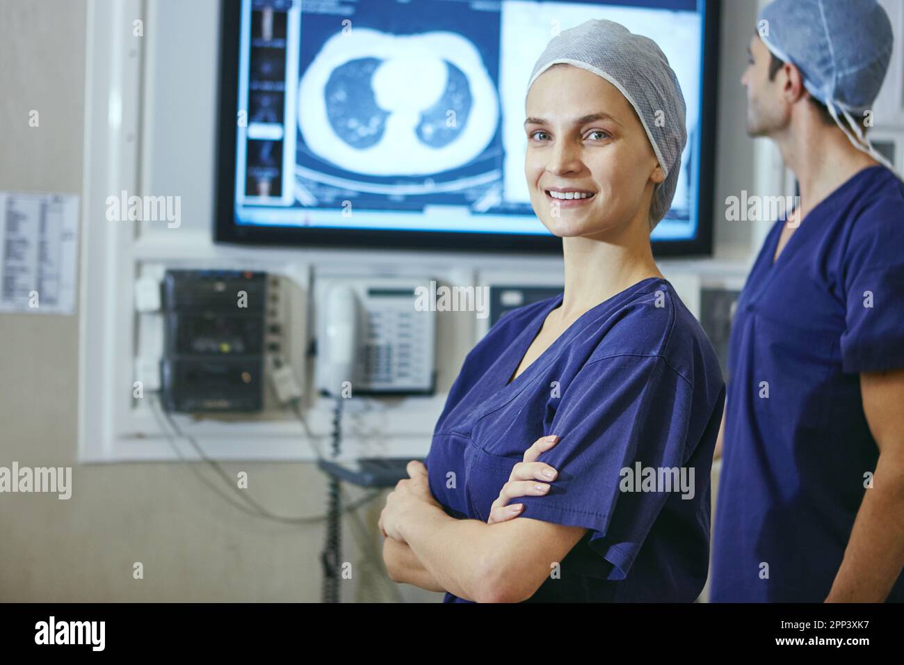 Ich bevorzuge Dr. statt Mrs. Portrait eines Chirurgen mit ihrer Kollegin, die sich im Hintergrund einen medizinischen Scan ansieht. Stockfoto
