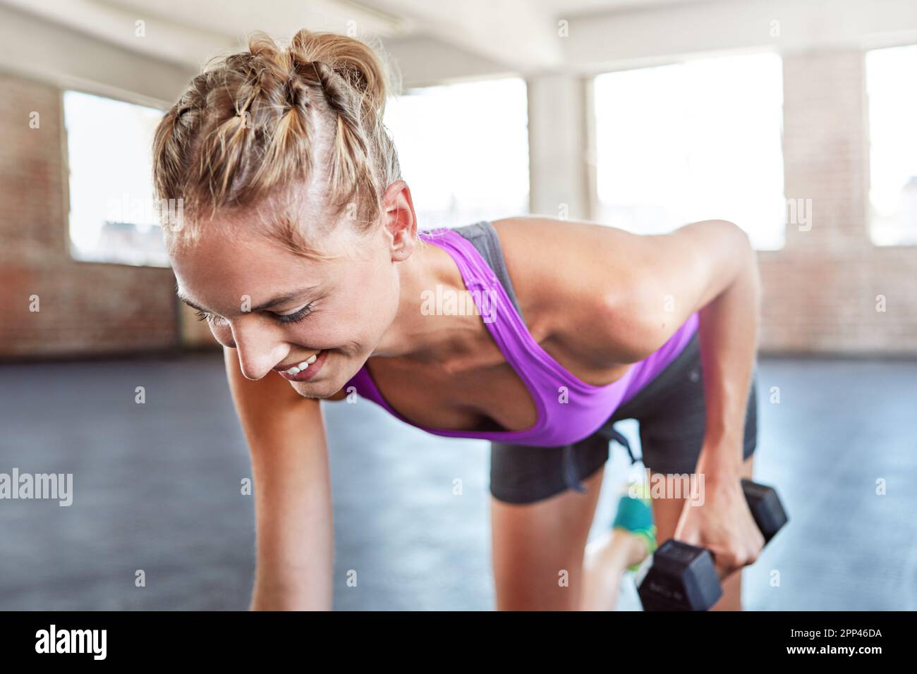 Es gibt keinen Gewinn ohne Schmerzen. Eine junge Frau, die im Fitnessstudio mit Gewichten trainiert. Stockfoto