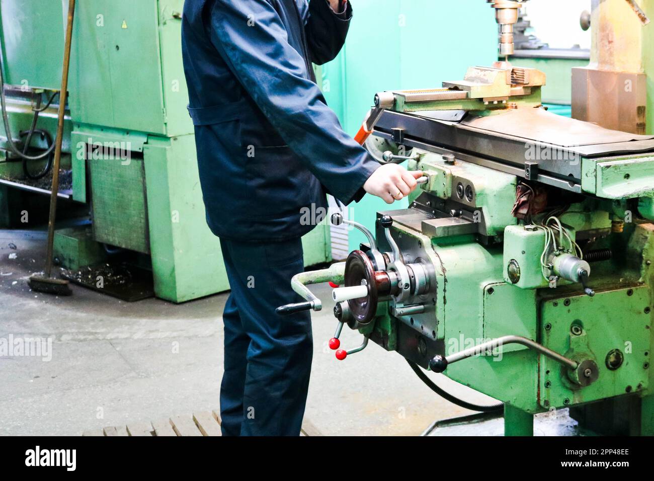 Ein männlicher Arbeiter arbeitet an einer größeren Metallschleusen-Drehmaschine, Ausrüstung für Reparaturen, Metallarbeiten in einer Werkstatt in einer Metallurgieanlage in einem Reparaturprogramm Stockfoto