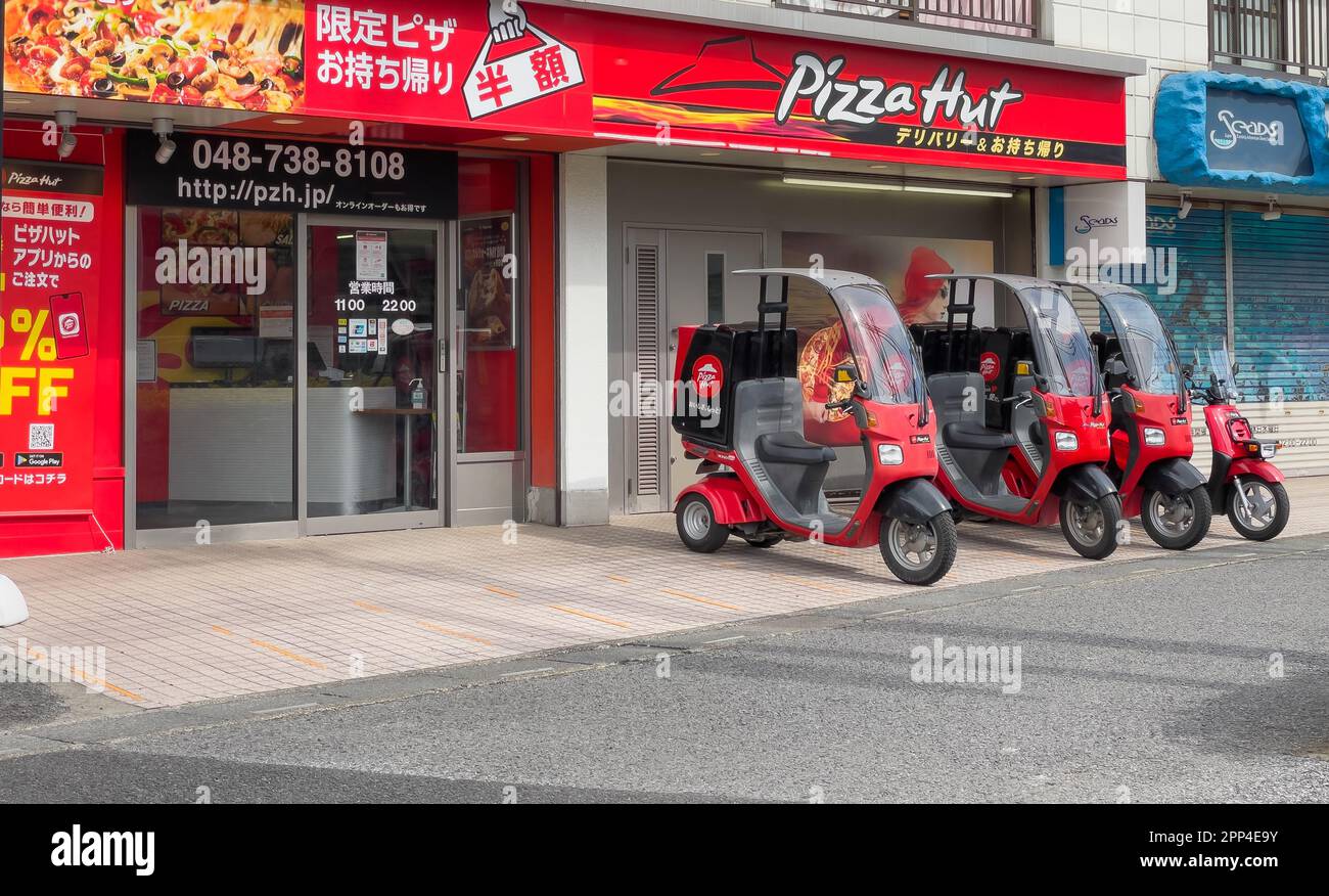 Ein Seitenbild von vier 3-rädrigen Pizza Hut Liefermotorrädern mit Dächern und einer Aufbewahrungsbox hinten mit Bildern des roten Pizza Hut Logos Stockfoto