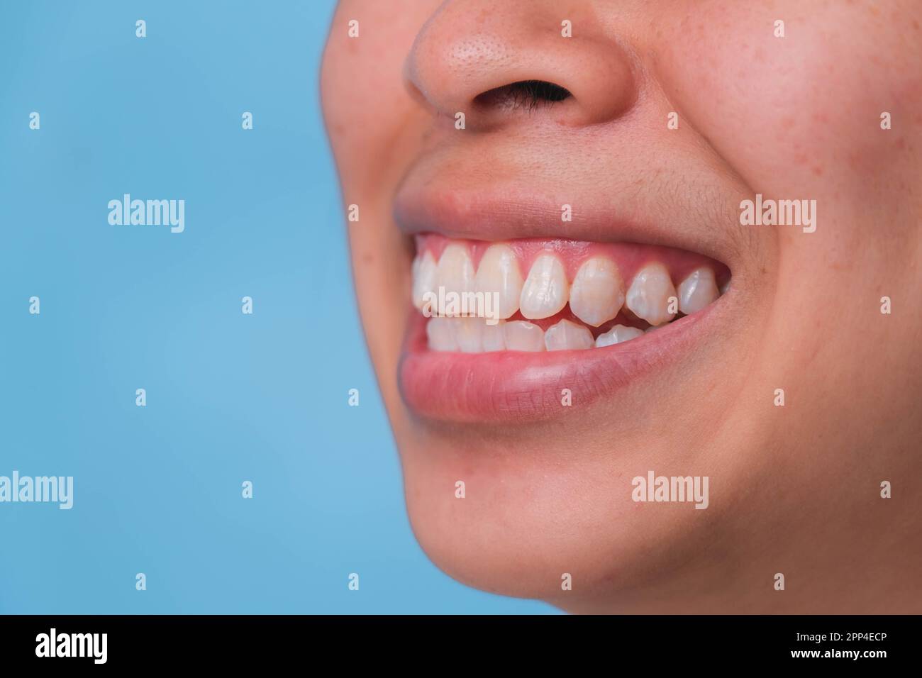 Nahaufnahme der Vorderansicht einer glücklichen asiatischen Frau, die weiträumig lächelt und ihre wunderschönen weißen Zähne auf pinkfarbenem Hintergrund enthüllt. Stockfoto