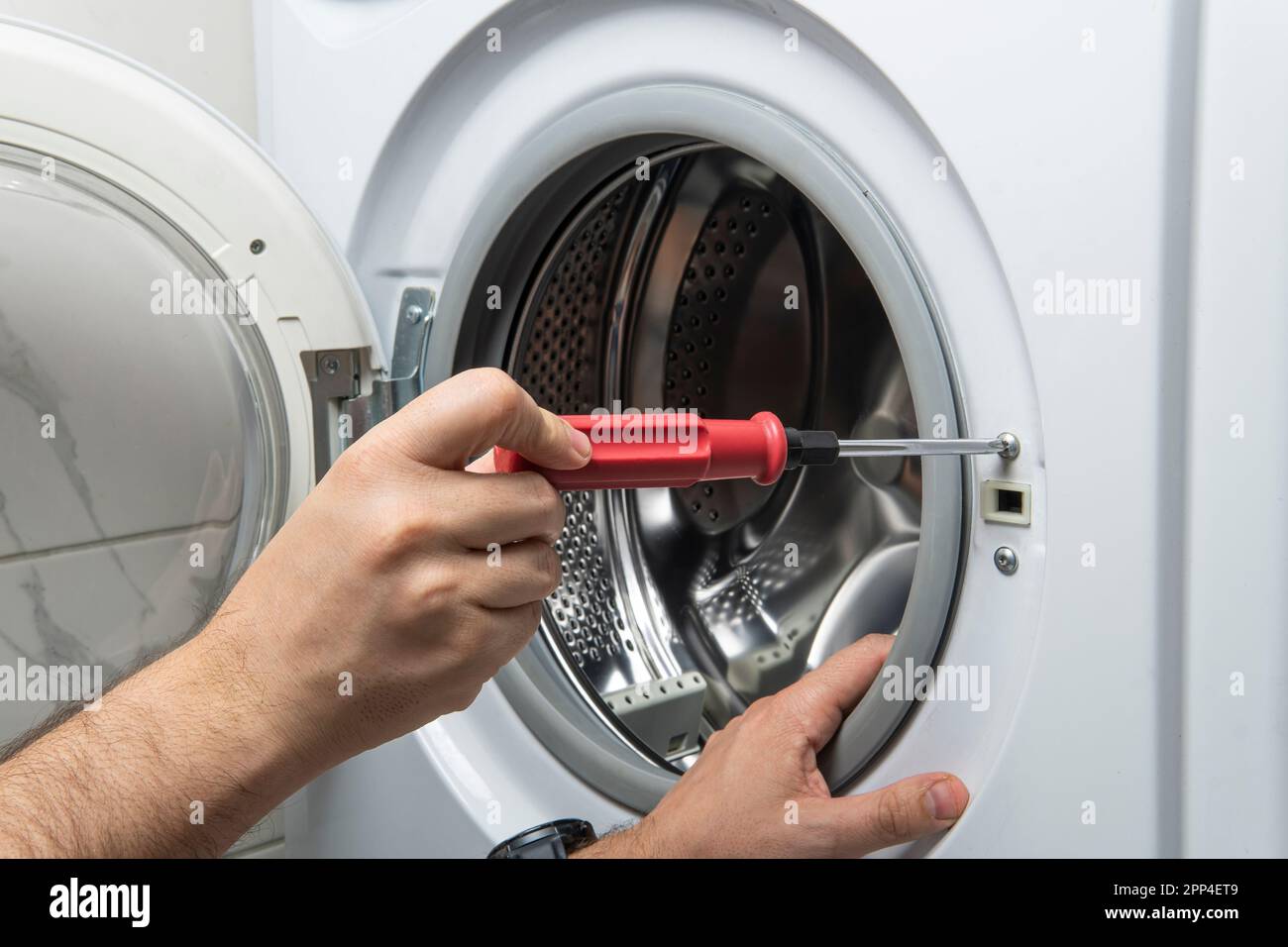 Junger Klempner, der Waschmaschine im Badezimmer fixiert, Nahaufnahme Stockfoto
