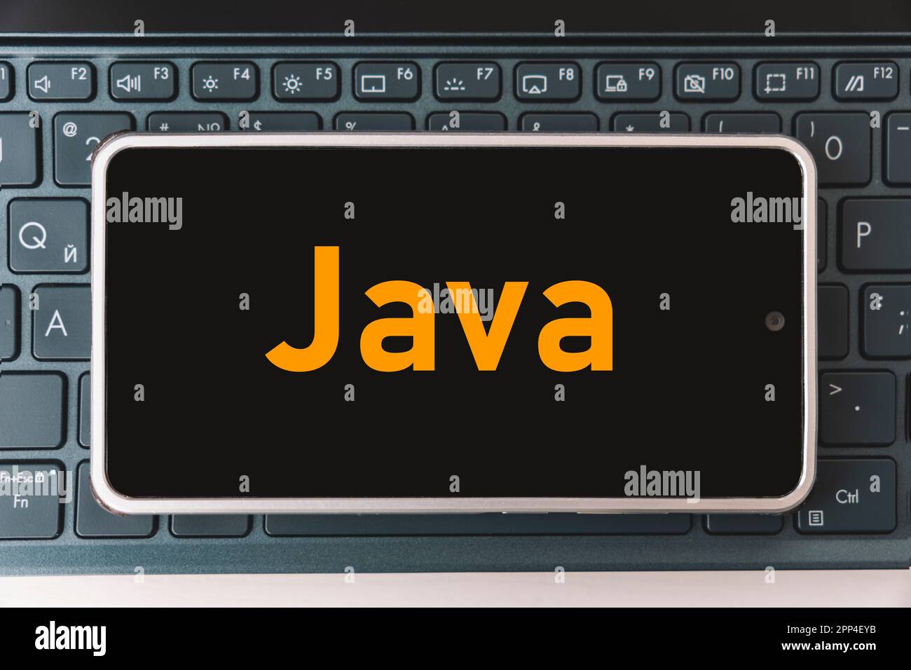 Java-Programmiersprache für die mobile Entwicklung, Konzept. Smartphone auf der Laptop-Tastatur, dem Arbeitsplatz des Programmierers. Inscription java auf dem Mobilgerät Stockfoto