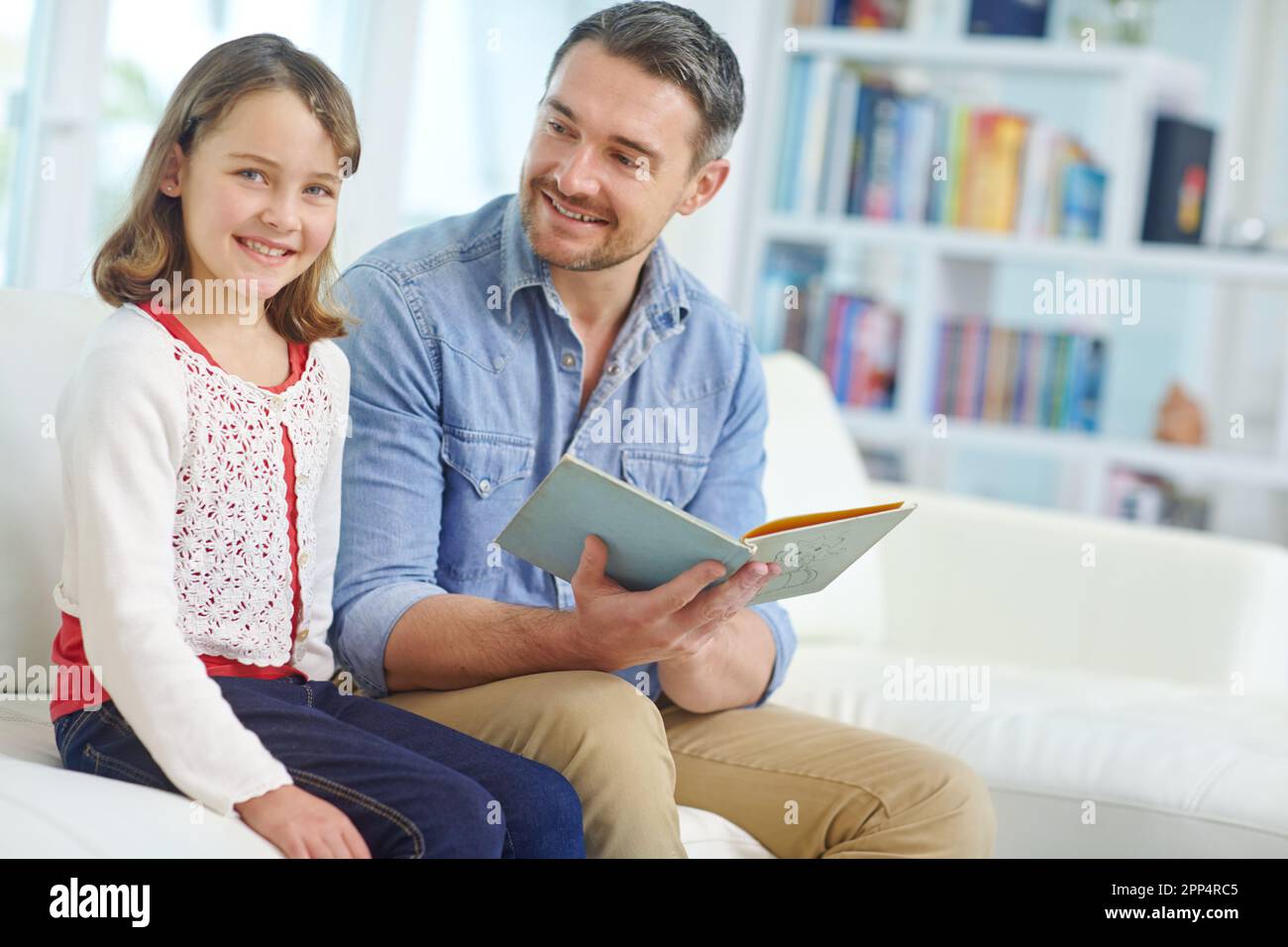 Daddy liest mir jeden Tag vor. Ein Vater, der seiner Tochter zu Hause eine Geschichte vorliest. Stockfoto