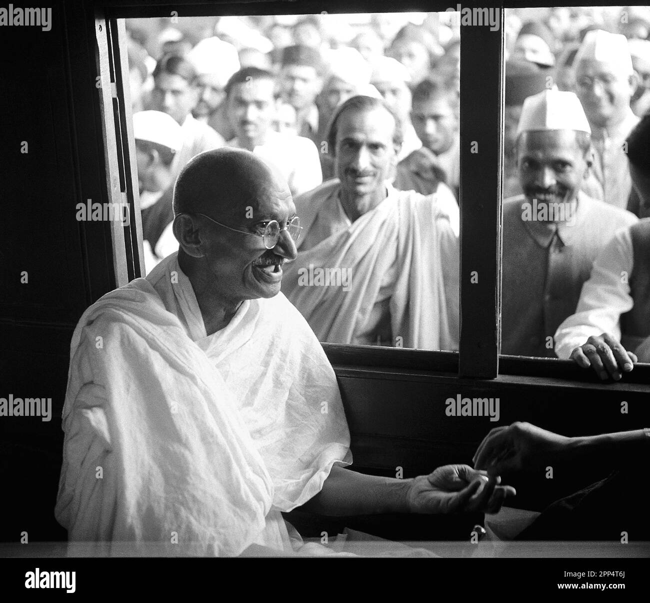 Mahatma Gandhi erhält eine Spende in einem Zugabteil. Acharya Kripalani und Radhakrishna Bajaj schauen durch das Fenster, 1940. Stockfoto