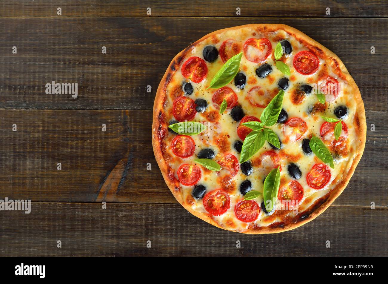 Hausgemachte Pizza mit Tomaten und Oliven auf Holzhintergrund mit Kopierraum. Draufsicht, flach liegend Stockfoto