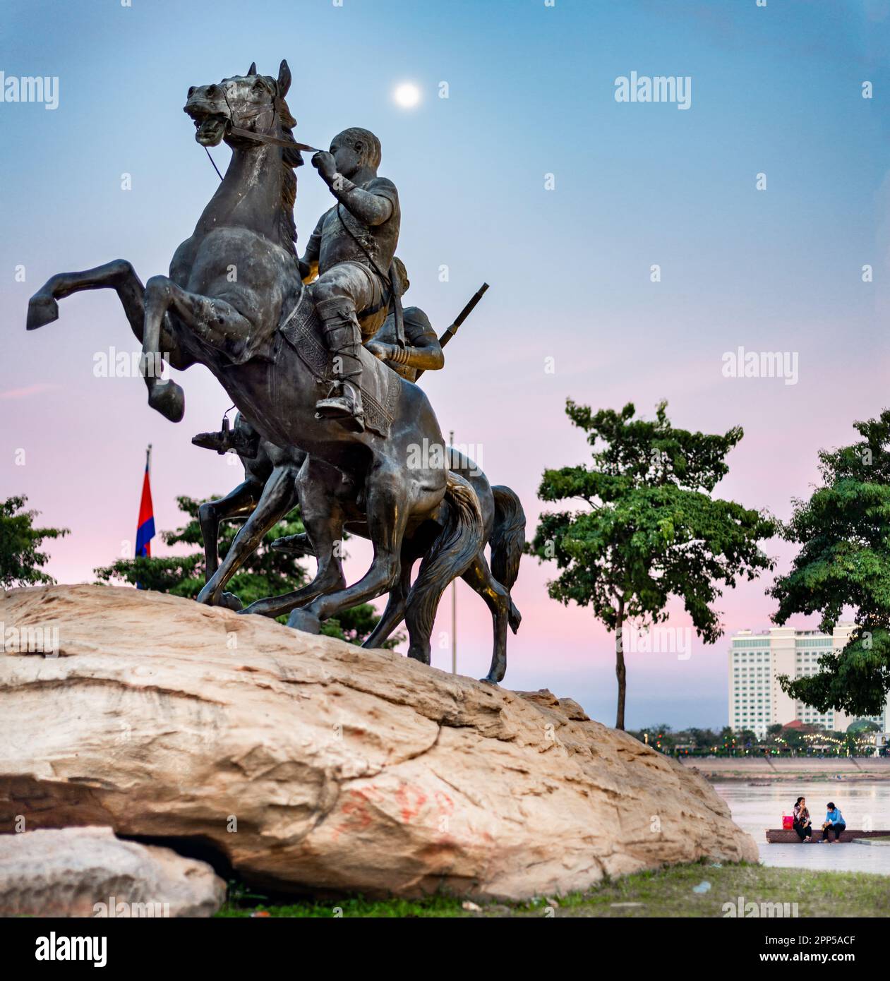 Historisches Denkmal von zwei lebensgroßen Pferden, mit ihren Khmer-Reitern, lebensgroß, hoch oben auf einem großen Felsen. Nach Sonnenuntergang, wenn der Mond am Himmel hängt, über einem Stockfoto