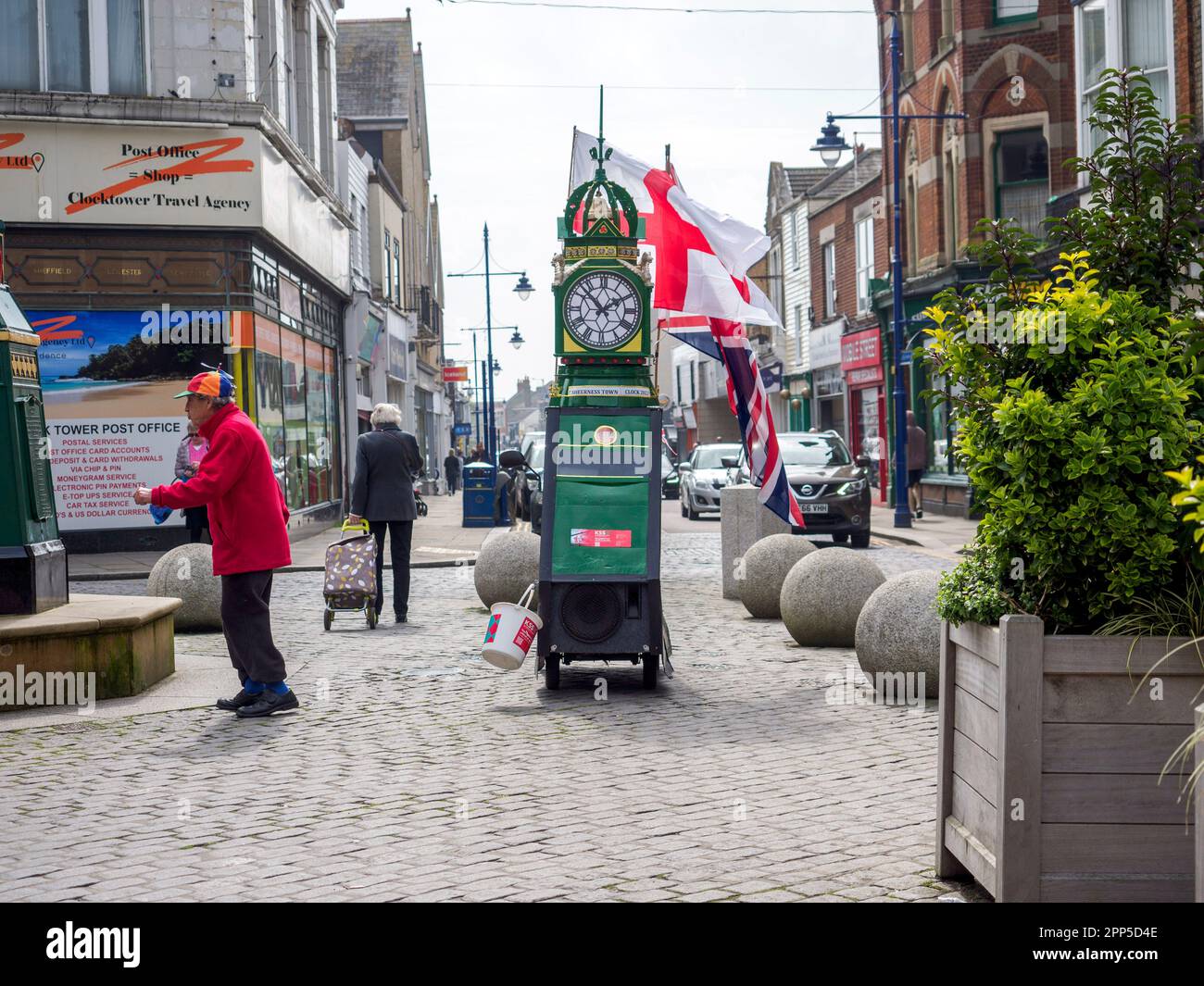 Sheerness, Kent, Großbritannien. 22. April 2023. Der lokale Spendensammler Tim Bell's (im Alter von 78 Jahren), der als Sheerness Clock Tower dekoriert ist, wurde gesehen, wie er die Flagge für St. George's Day neben dem echten Sheerness Uhrenturm in Kent heute mit dem Ziel, Geld für den Kent Surrey Sussex Air Ambulance zu sammeln. Kredit: James Bell/Alamy Live News Stockfoto