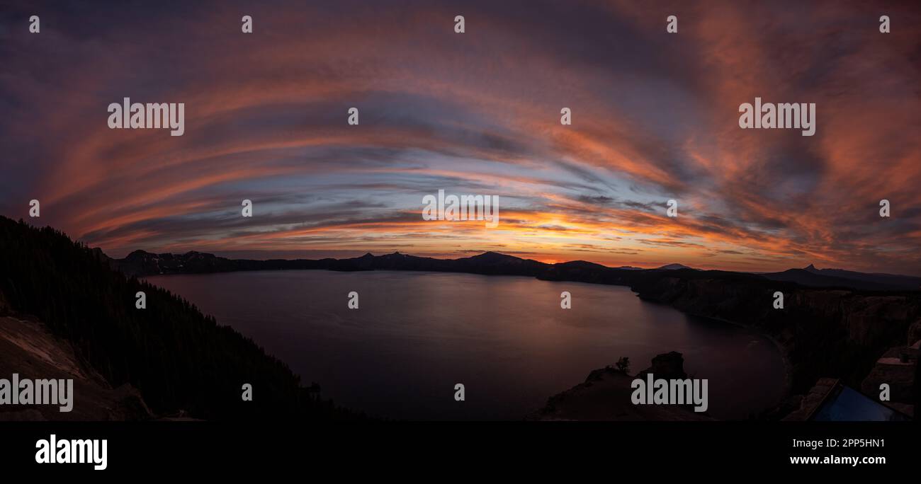 Panoramablick auf die rosafarbenen Wolken, die sich bei Sonnenuntergang über den Crater Lake schlängeln Stockfoto