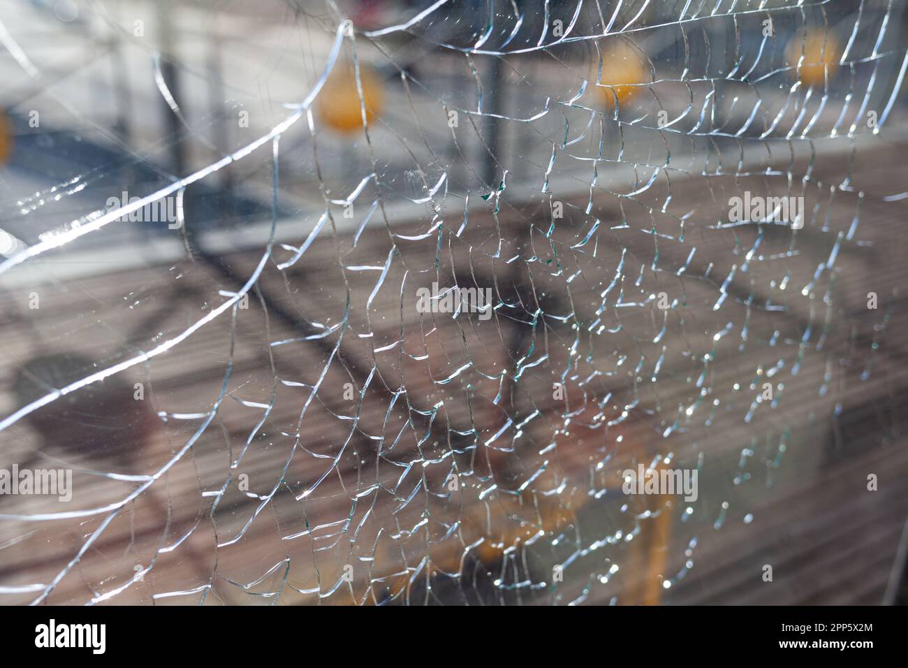 Zerbrochenes Glas, Risse am Fensterglas. Es gibt einen Fluss und eine Stadt im Hintergrund. Vandalismus. Stockfoto