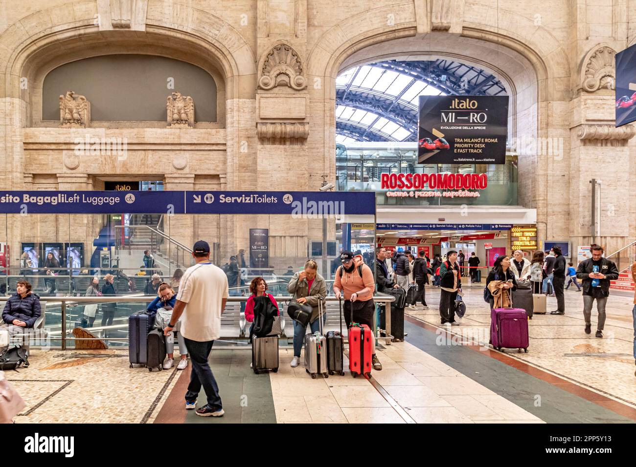 Bahnpassagiere warten mit Gepäck im großen Inneren der Haupthalle im Mailänder Hauptbahnhof, Mailand, Italien Stockfoto