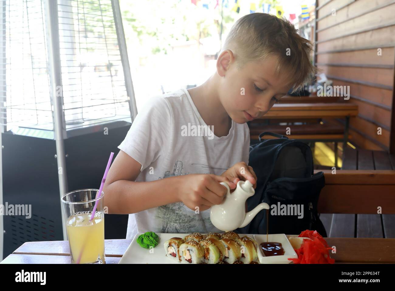 Kind gießt Sojasauce in Sushi-Restaurant ein Stockfoto