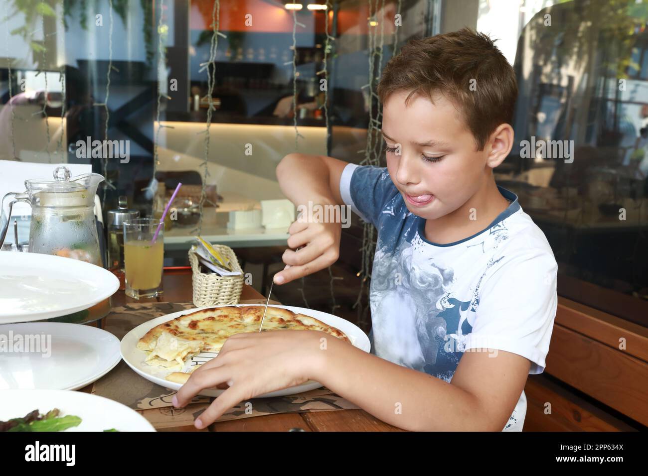 Das Kind teilt sich vier Käsepizza im Restaurant Stockfoto