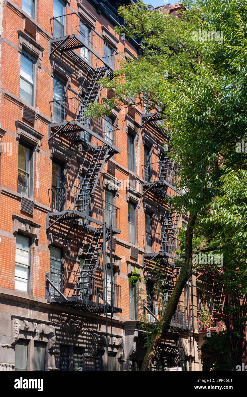 Ein altes Gebäude aus rotem Backstein mit einer Feuertreppe. New York City, USA - 20. August 2022. Stockfoto