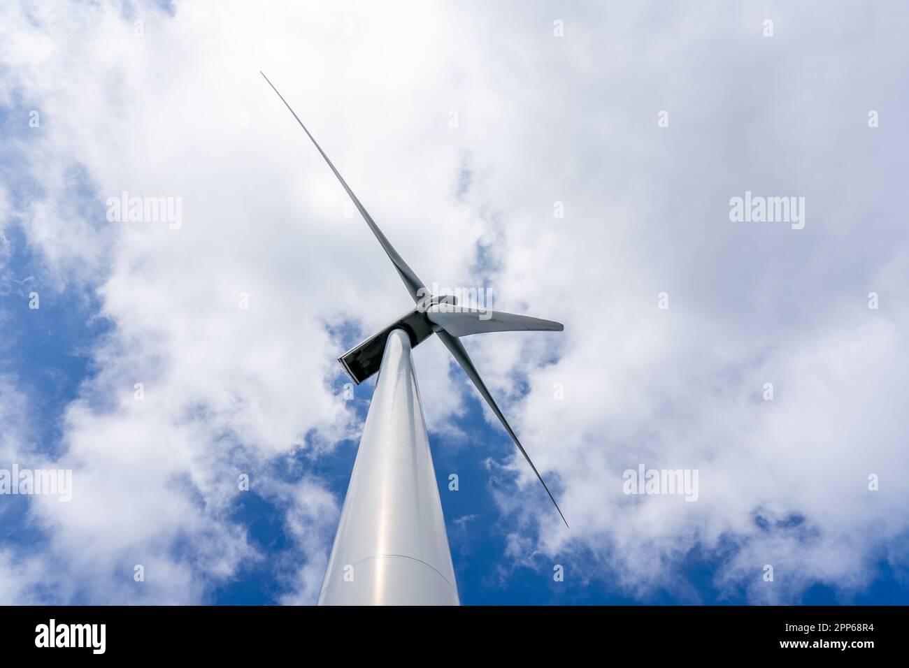 Ansicht von unten auf eine Windturbine, die Elektrizität erzeugt saubere Energie mit Wolken- und Sonnenlicht-Hintergrund am Himmel. Konzept für saubere Energie. Hochwertiges Fotopapier Stockfoto